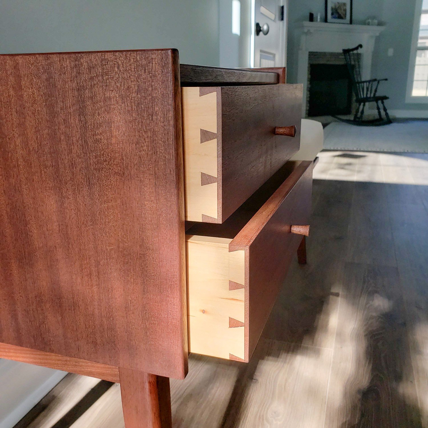 Angled view of the handmade walnut Gossip Bench showing the drawers, side panel, and dovetail construction.