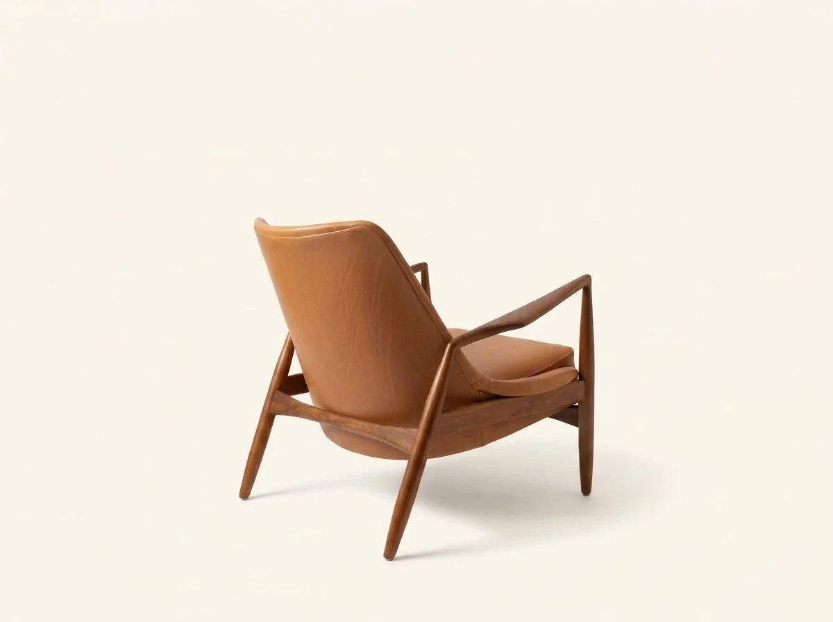 Three-quarter rear view of the restored Seal lounge chair showing the curved leather back and sculpted walnut frame.