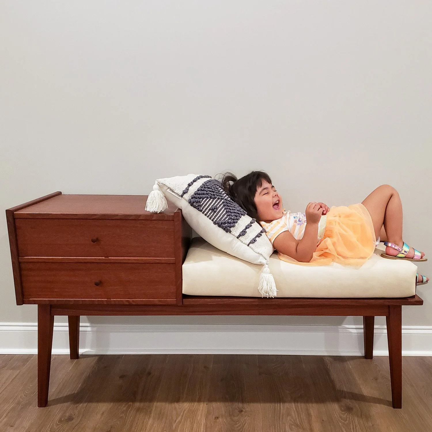 Handmade walnut Gossip Bench shown in use with its upholstered seat and built-in drawers.
