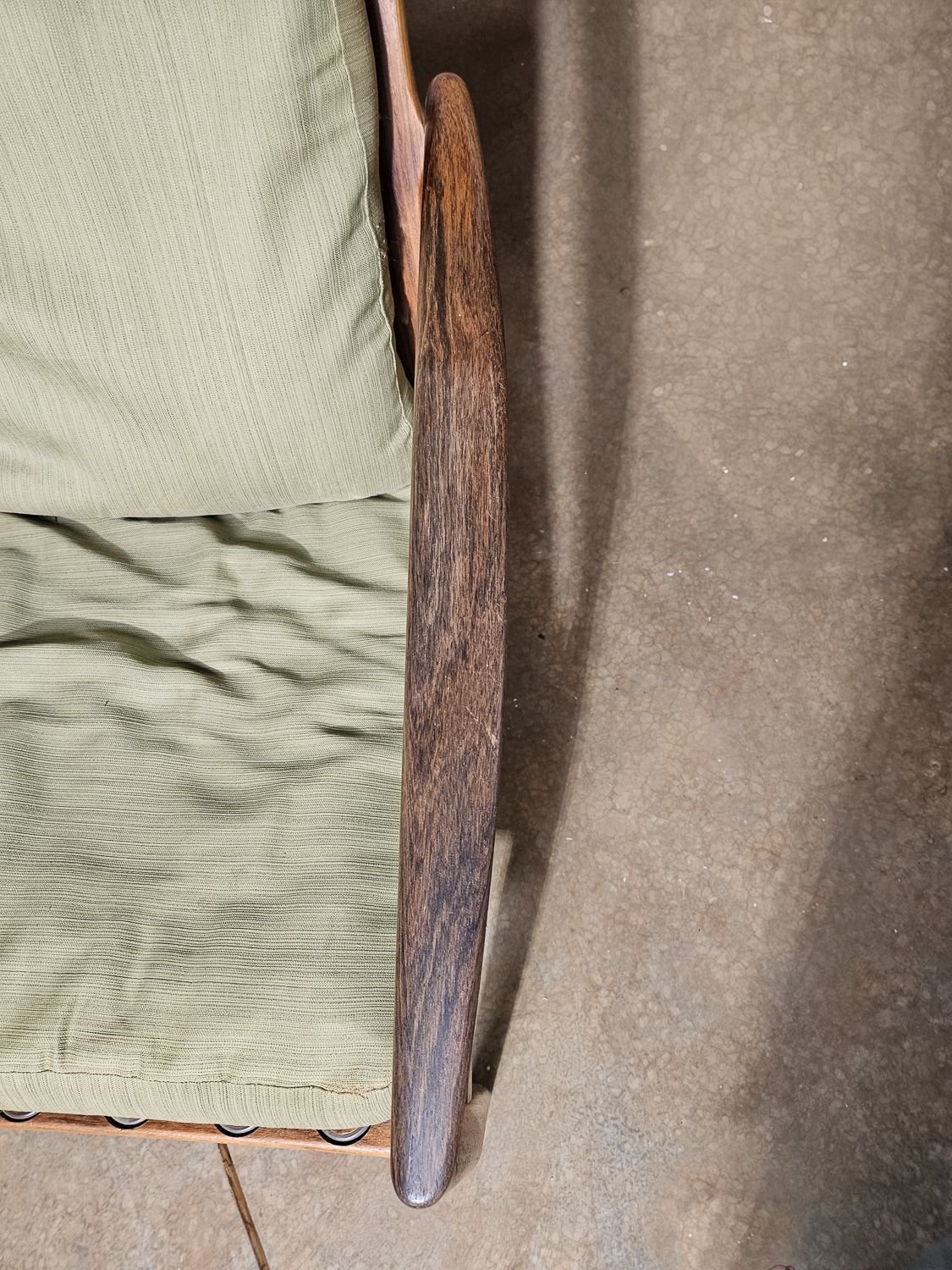 Close-up of the sculpted rosewood armrest on a Kai Kristiansen Model 121 Paper Knife chair, showing the dark figured grain and curved profile.