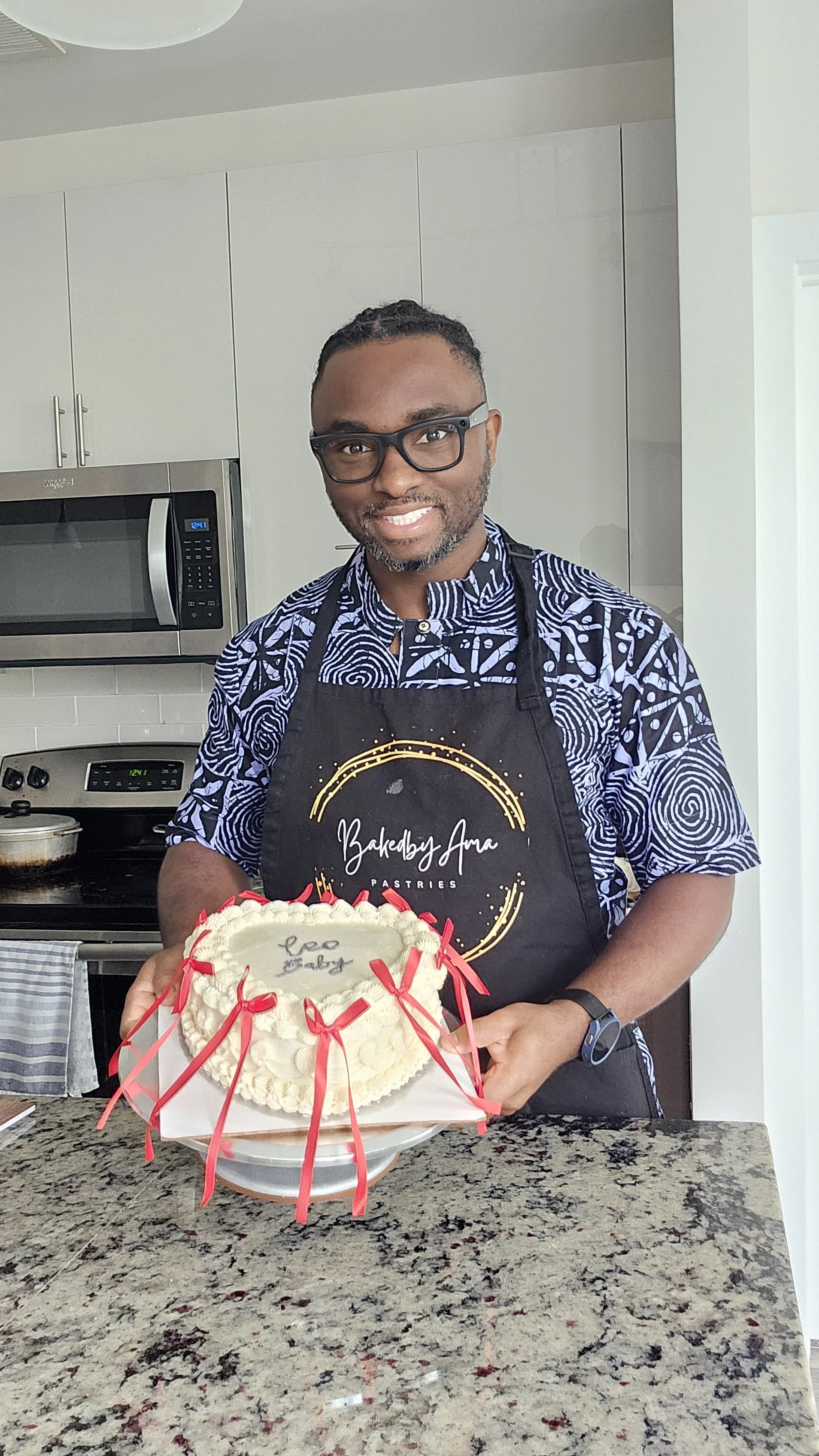 bakedbyAma baker holding a red and white ribbon decorated vintage celebration cake.