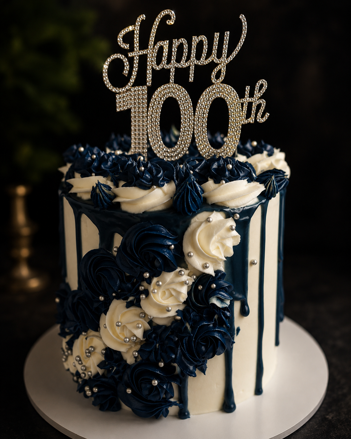 Blue and white birthday cake with silver accents and a Happy 100th topper.