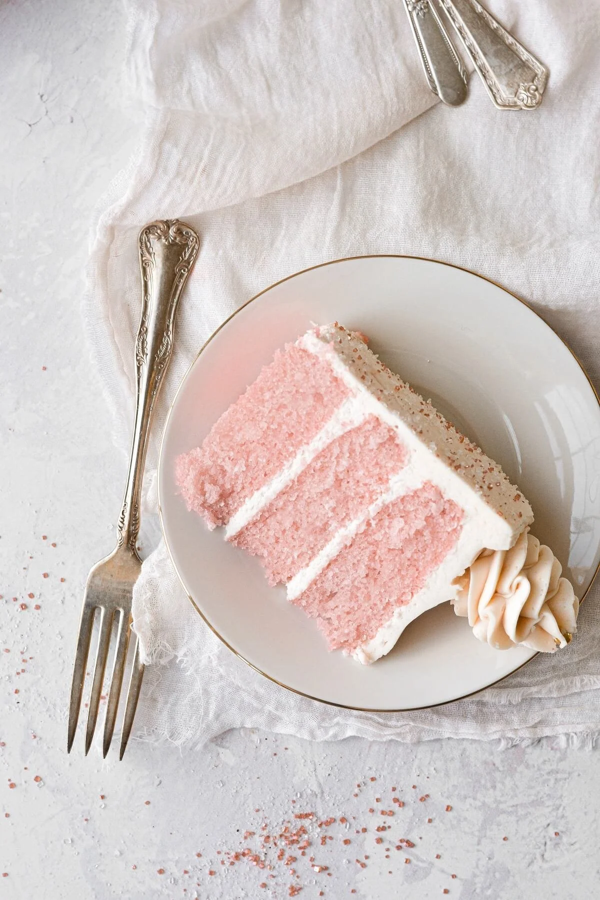 A slice of pink champagne cake and white frosting.