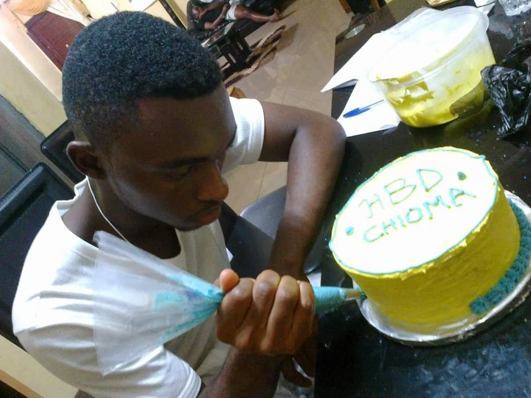 bakedbyAma baker piping colorful decorations onto a yellow birthday cake.
