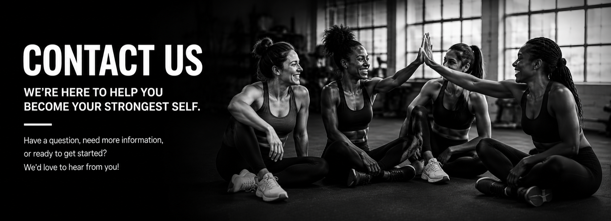 Four women in athletic clothing sitting on the floor in a gym, giving each other high fives, smiling, with large windows and gym equipment in the background.