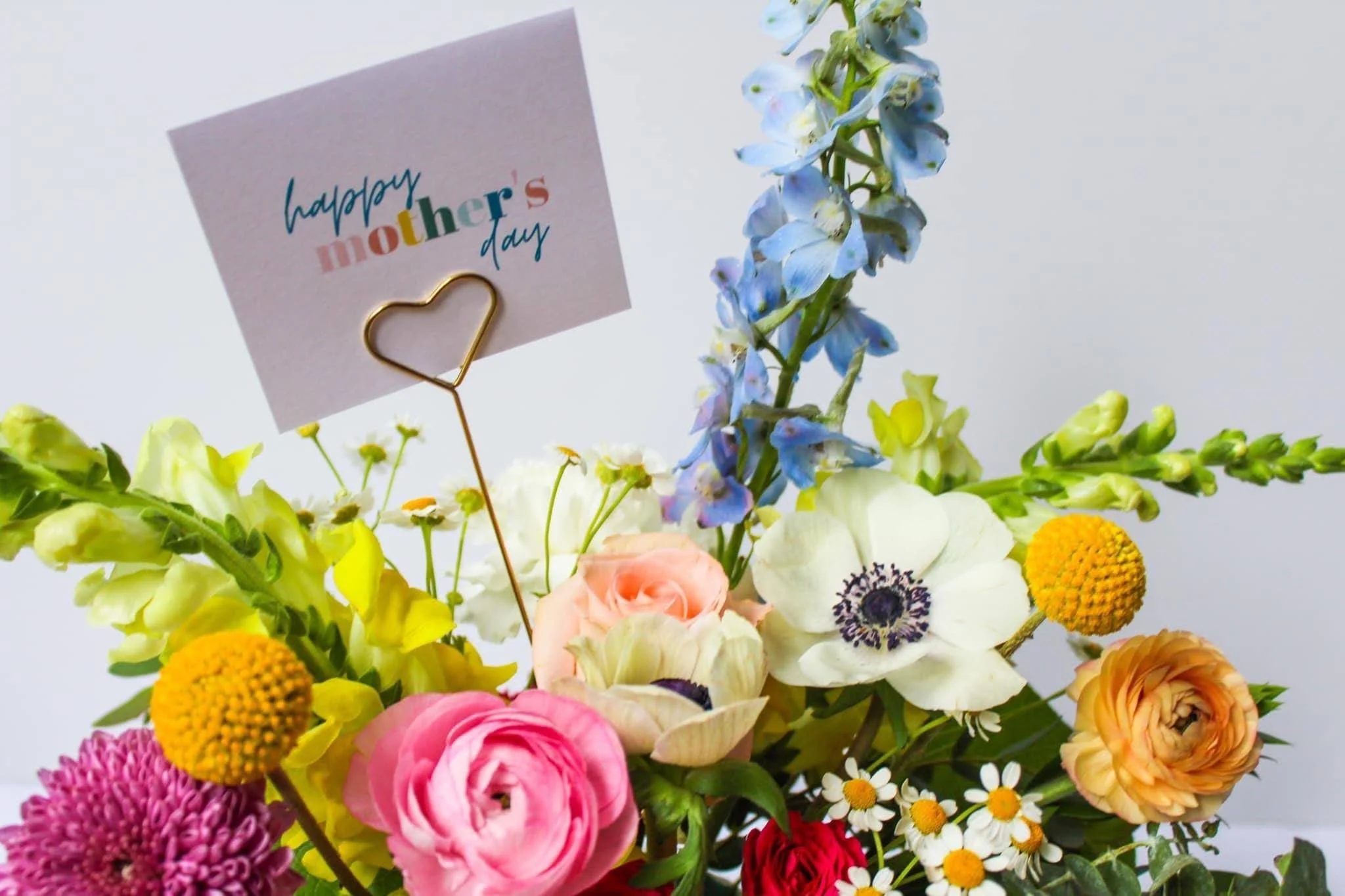 A colorful bouquet of various flowers with a 'Happy Mother's Day' card on a stick.