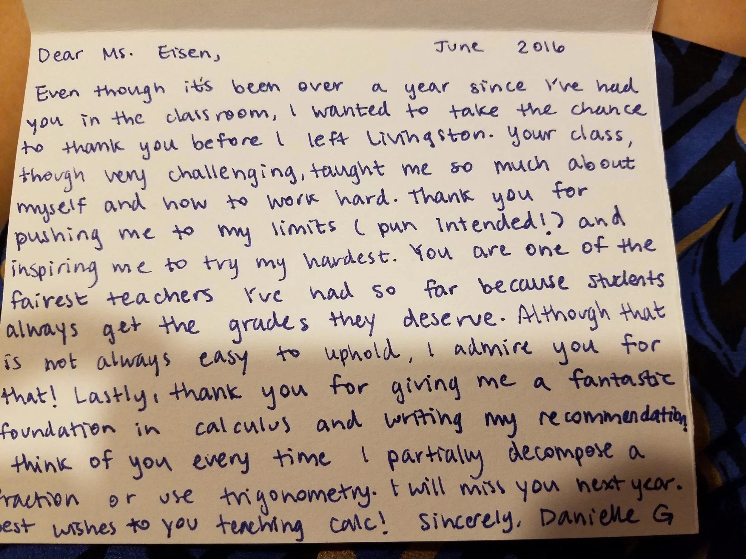 A handwritten letter on white paper addressed to Ms. Eisen, dated June 2016. The letter expresses gratitude and reflects on a past experience, with visible blue and black striped fabric partially underneath the paper.