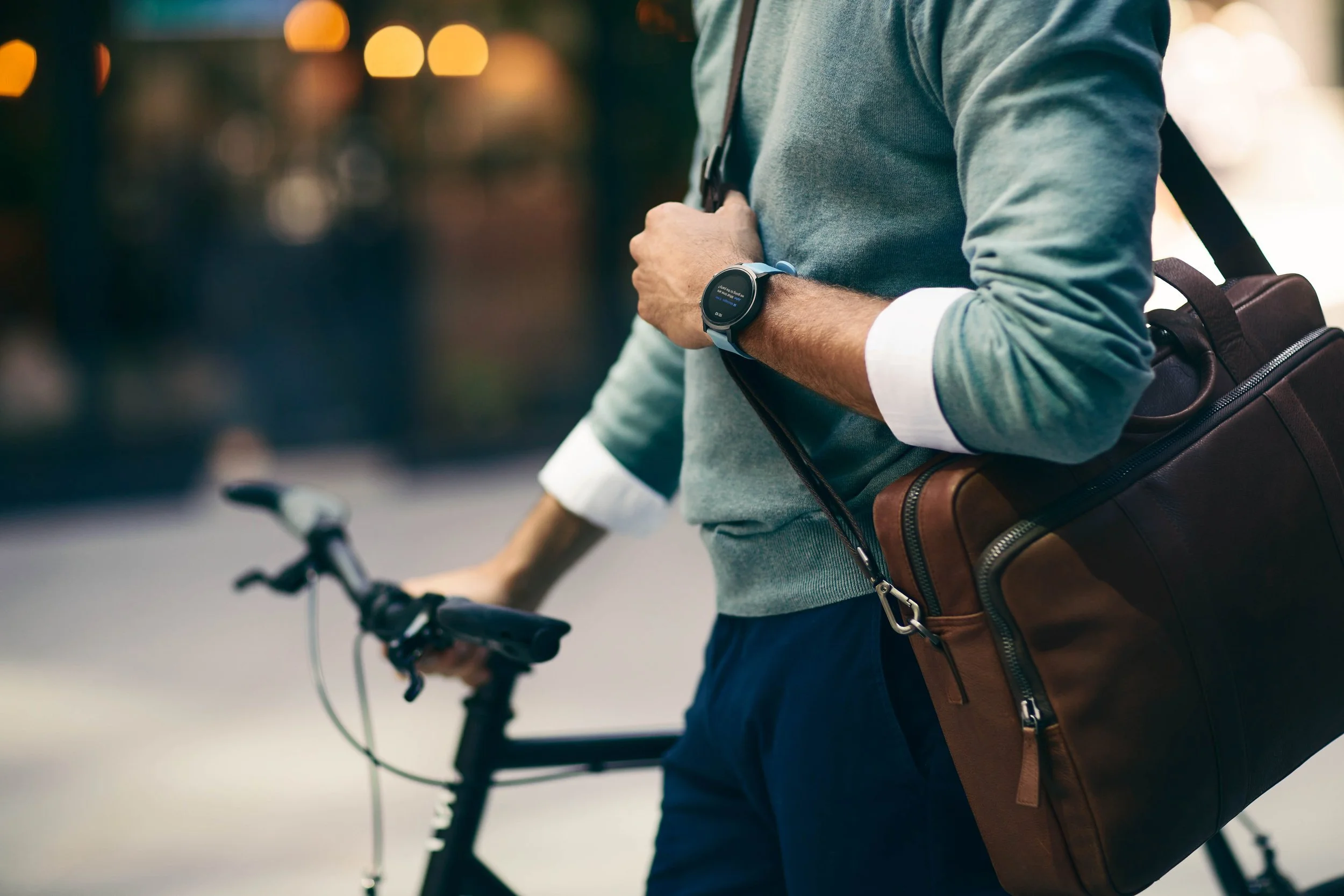 A man wearing a smart watch pushes his bike through the city of London. Photography by lifestyle photographer Jon Enoch.