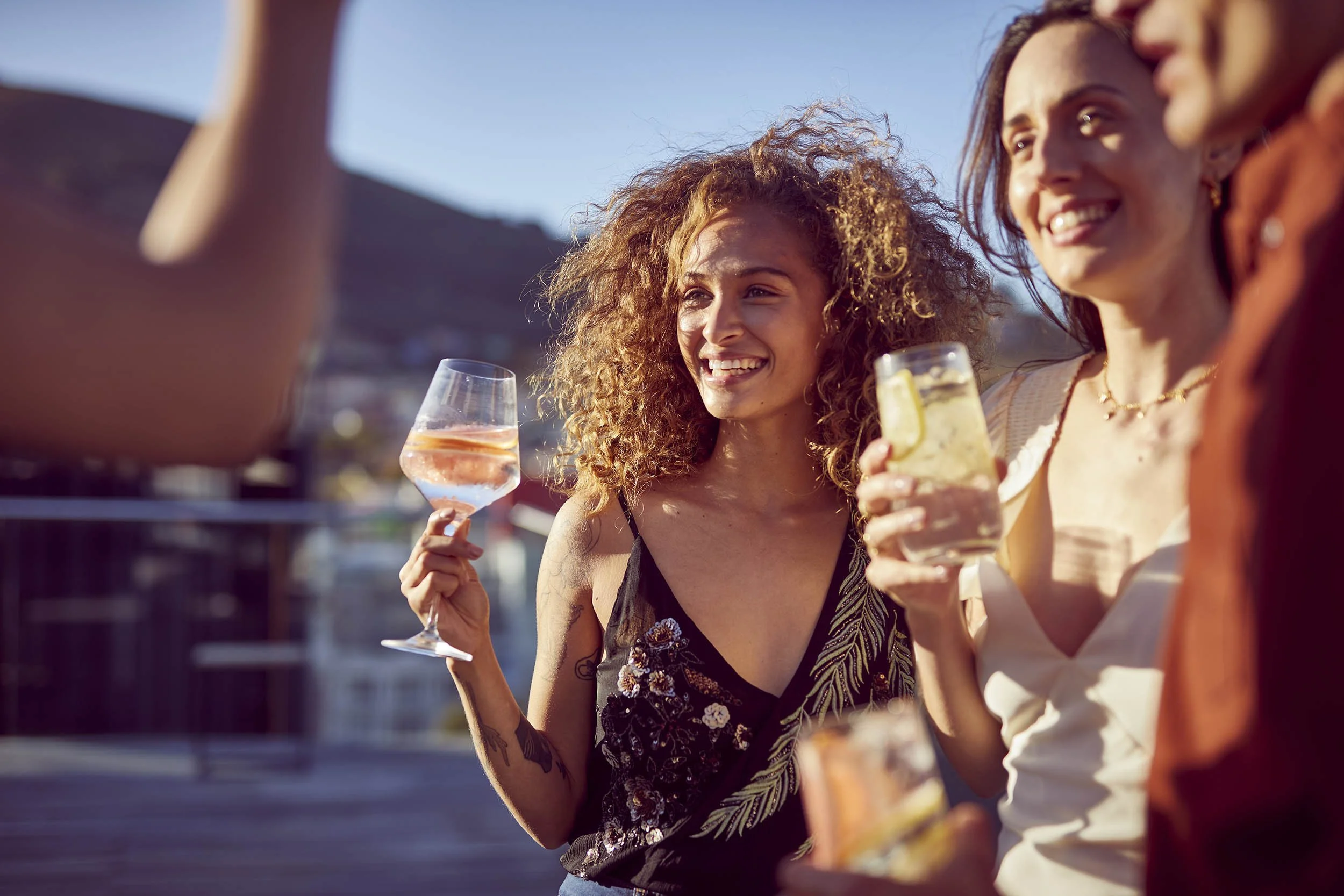 Friends party on a rooftop in the summer light - drinks in hand in this drinks image by Jon Enoch