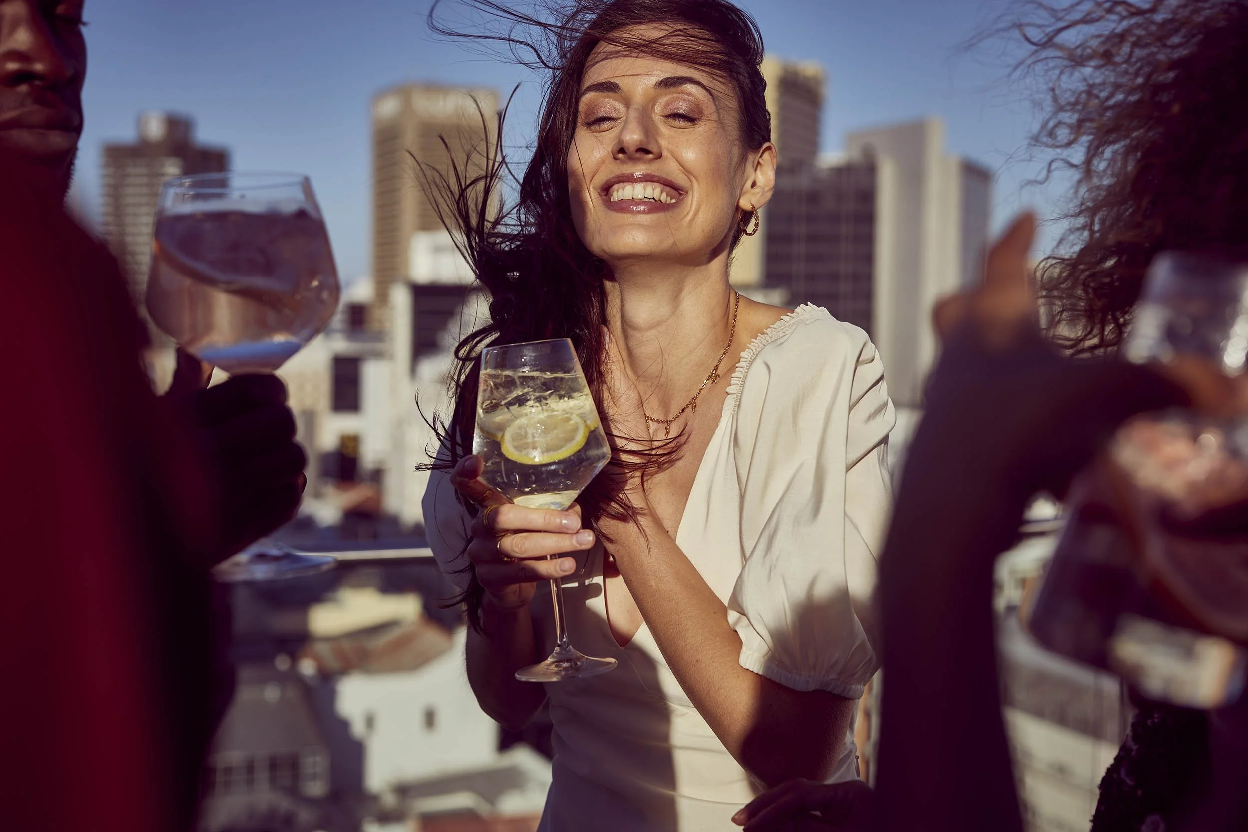 Lifestyle photography capturing friends enjoying drinks on a rooftop terrace at sunset.