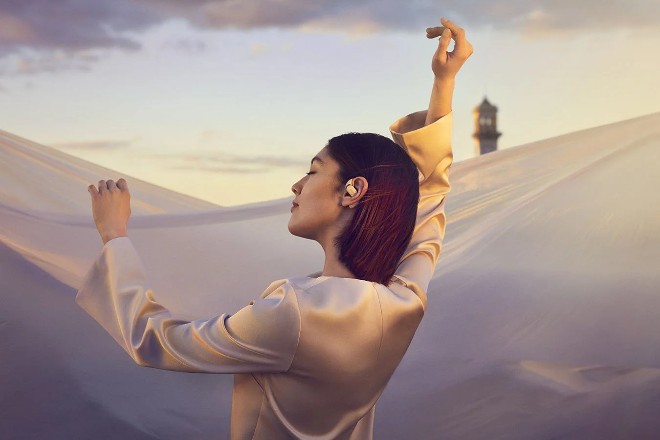Lifestyle photography created for Shokz, featuring a woman enjoying music at sunset while wearing wireless headphones.