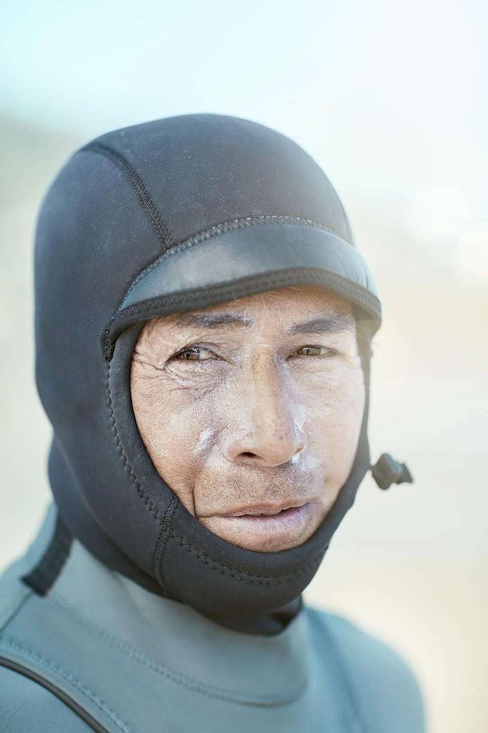 A surfer poses for a portrait after his morning surf on a beach just South of San Francisco California, USA. Photography by Jon Enoch.