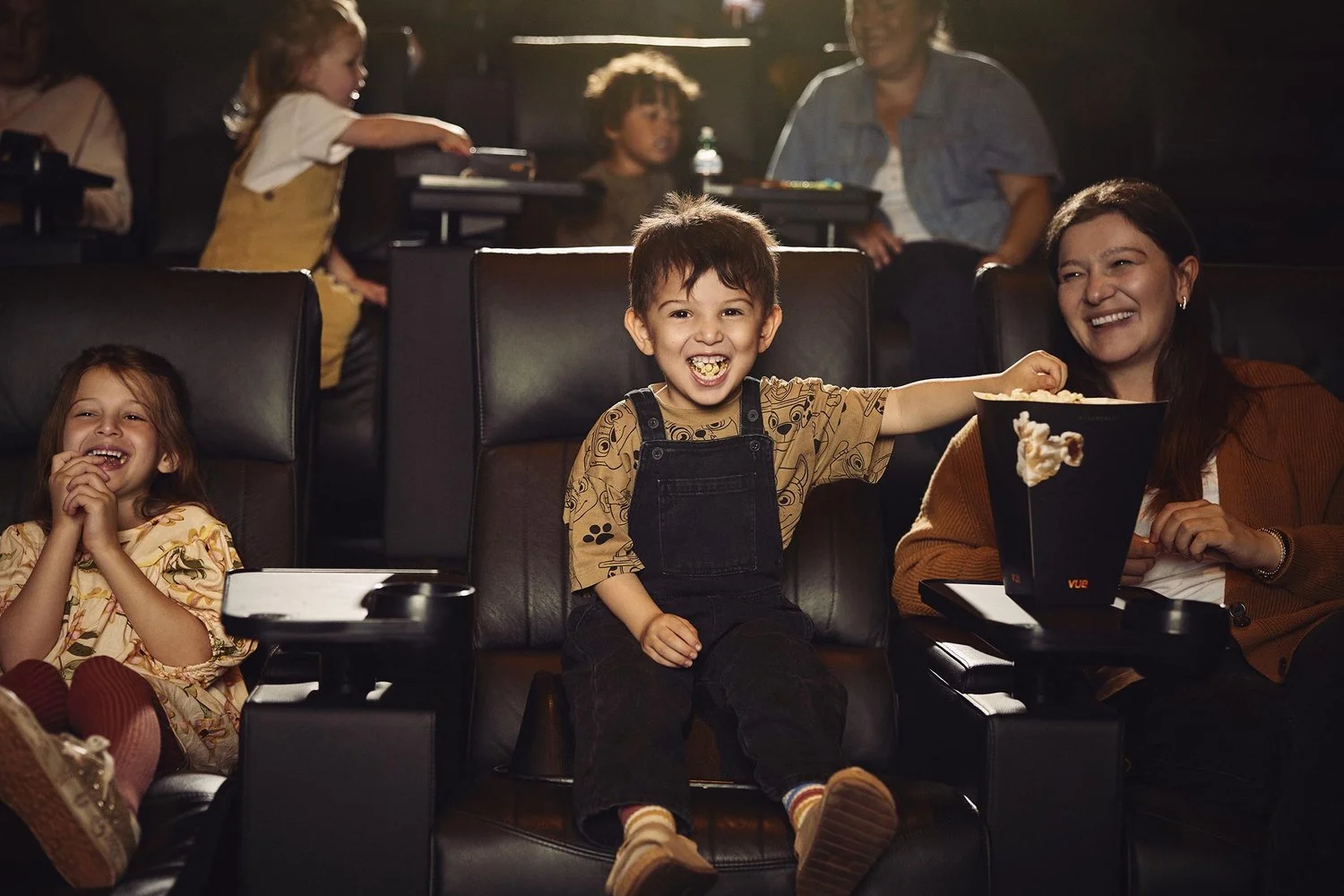 A young boy grabs a handful of popcorn whilst watching a film at a Vue cinema in this advertising image by photographer Jon Enoch