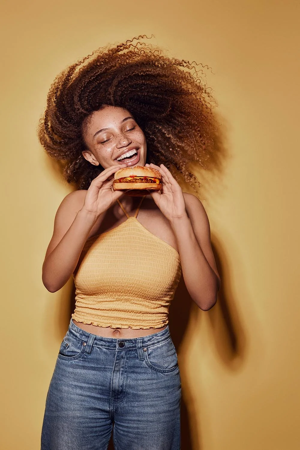 A teenager pulls a crazy face whilst enjoying a burger - lifestyle photography by Jon Enoch