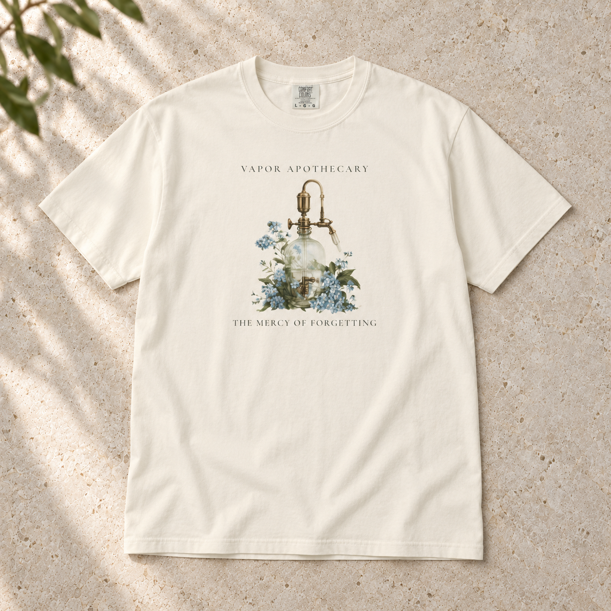 The Mercy of Forgetting T-shirt in Ivory, flat-lay mockup