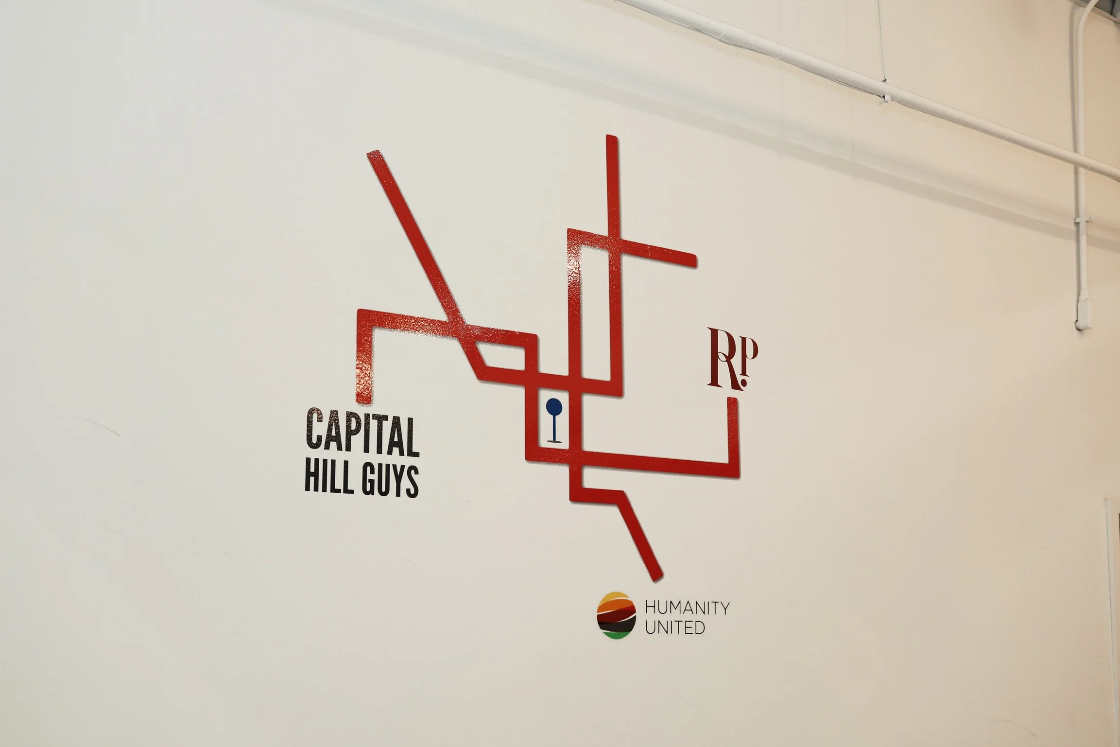 A red map of the Washington, D.C. metro stops on a white wall, with labels for 'CAPITAL HILL GUYS' and 'HUMANITY UNITED' at the bottom.