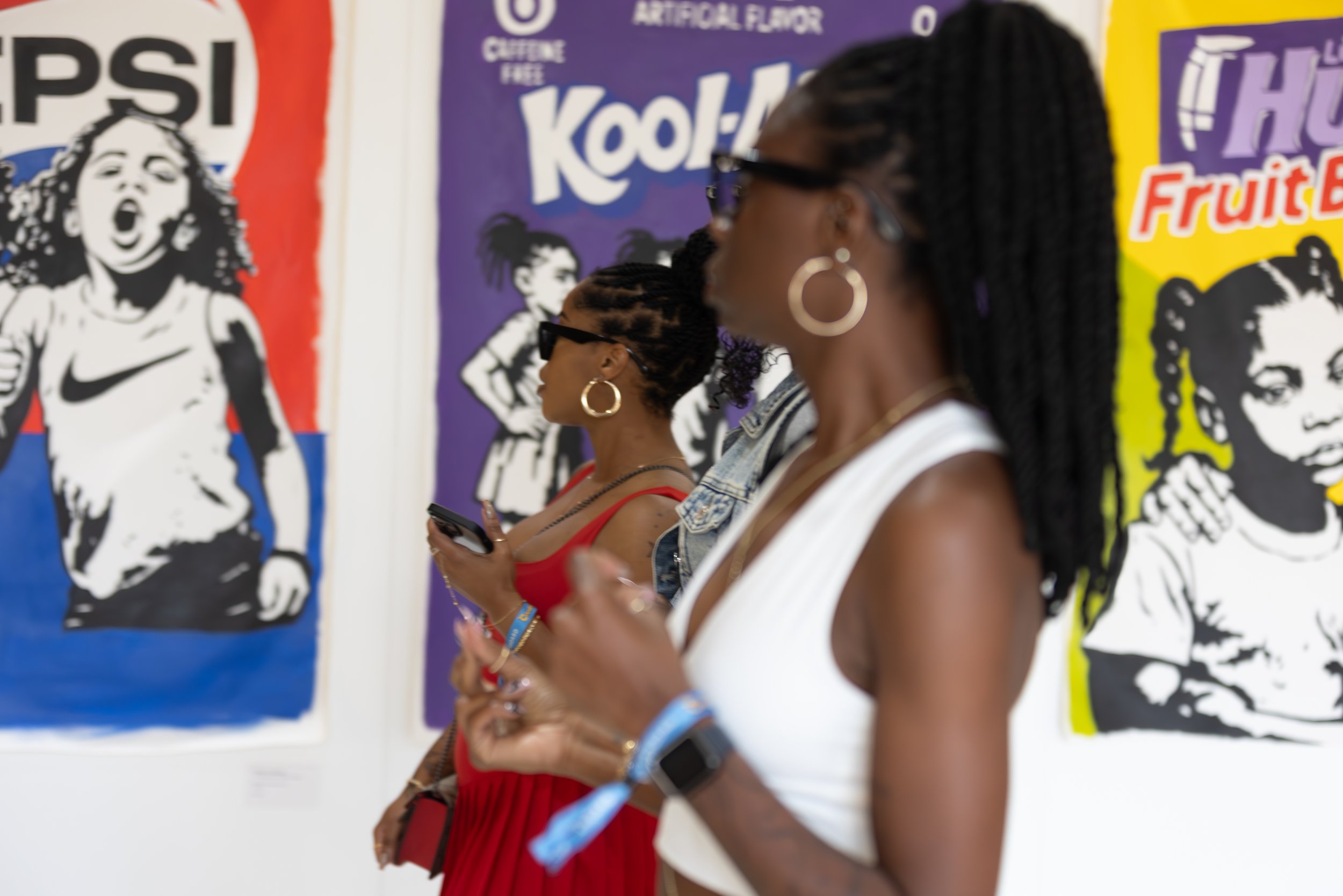 People standing in front of colorful graffiti-style posters at an art gallery.