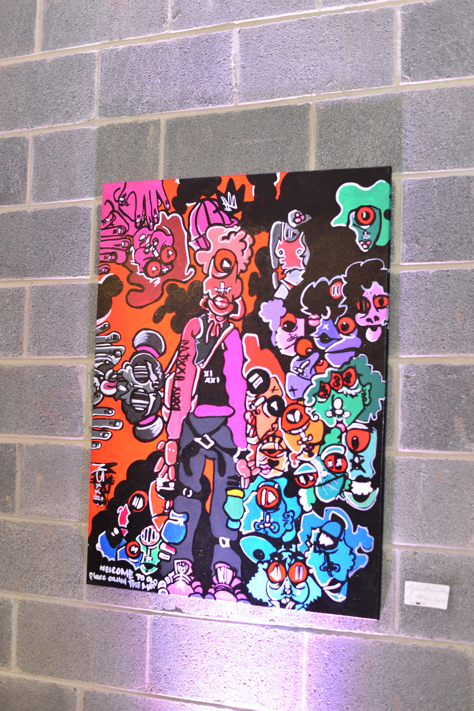 Colorful graffiti art on a black wall featuring abstract cartoon characters with exaggerated facial features, bright colors, and stylized designs. The artwork includes various faces and figures with vibrant and bold outlines.