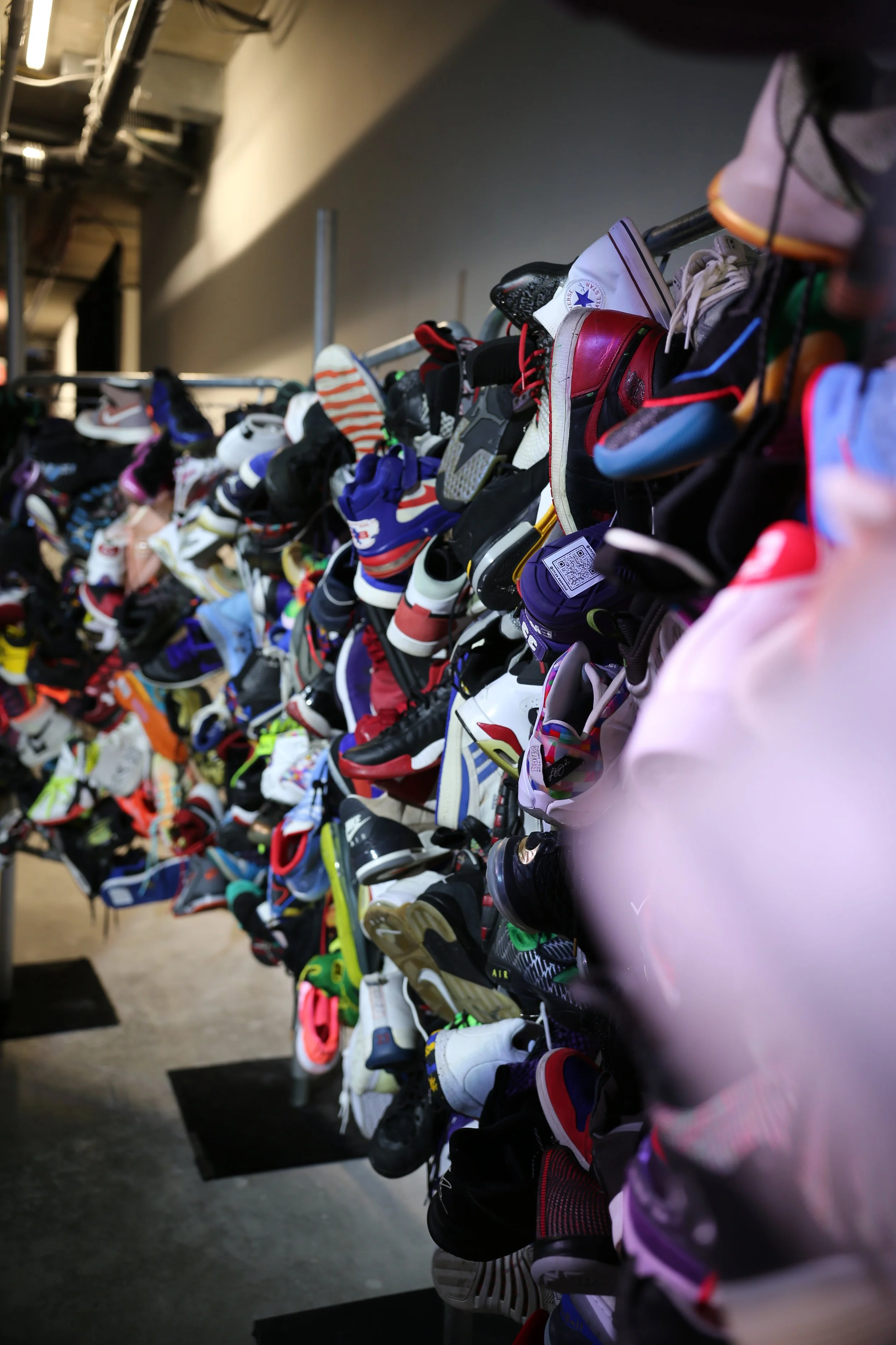 A display of various sneakers and athletic shoes on a multi-tiered shelf in a store.