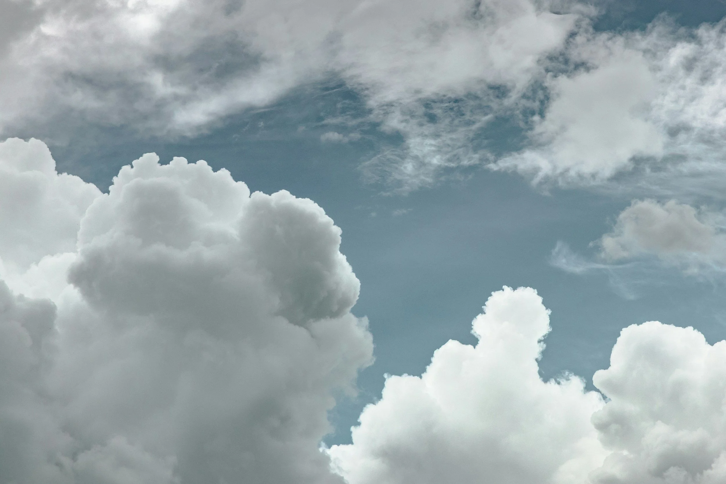 Cloudy sky with various sizes and shapes of white and gray clouds.