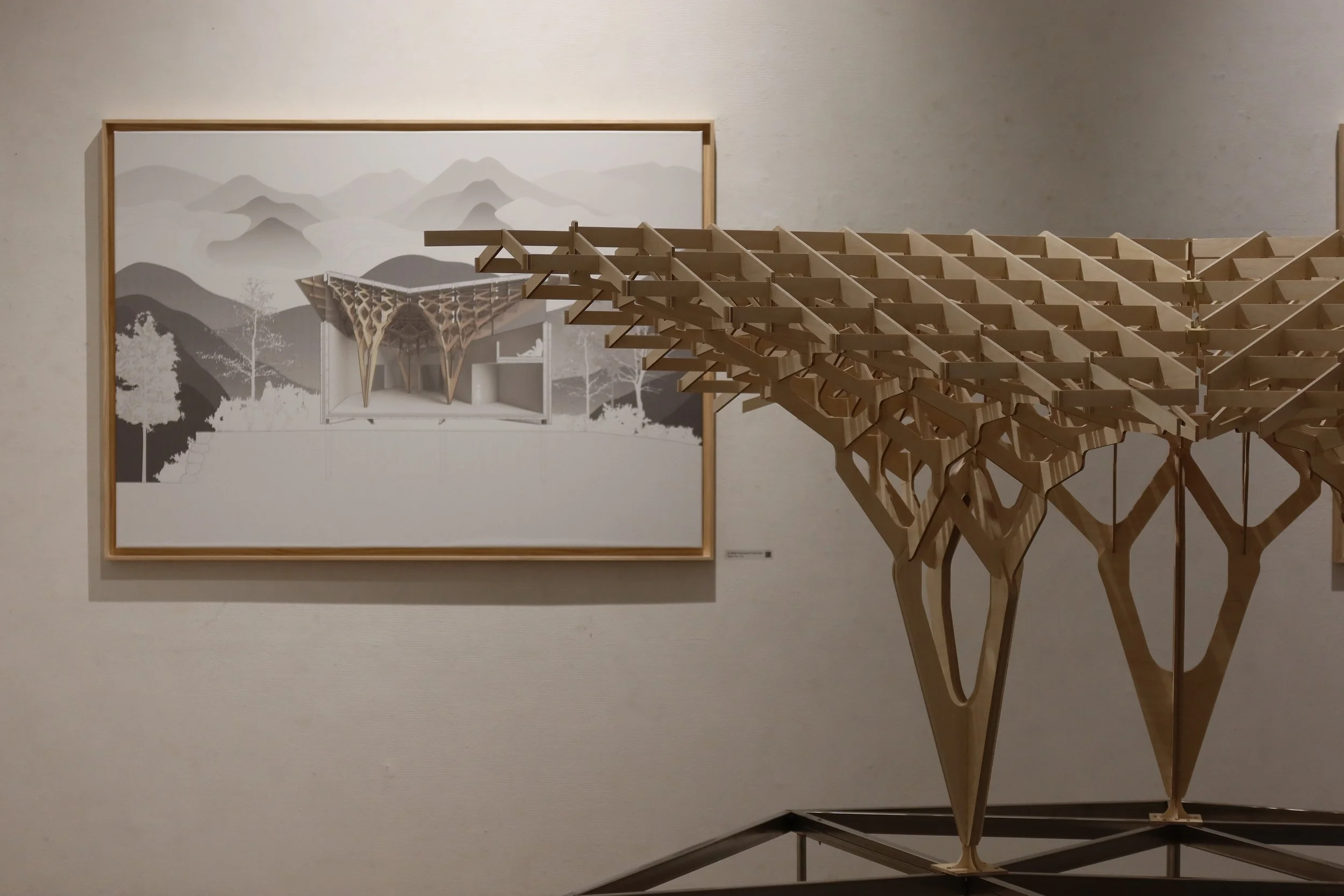 Wooden architectural model of a bridge or structure with a framed art piece of mountains in the background.