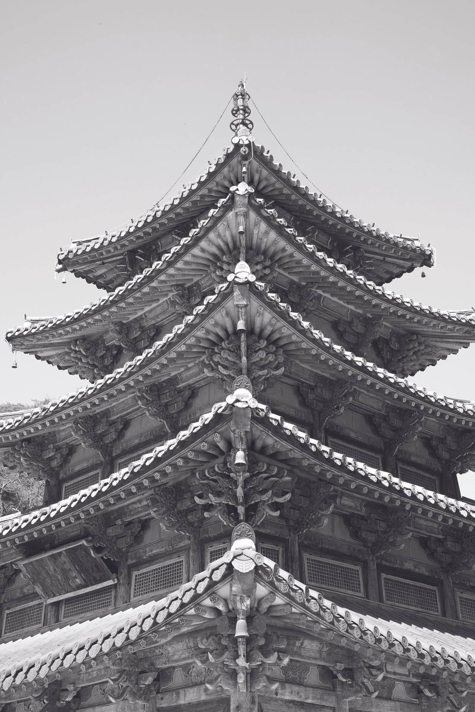 Black and white photograph of the intricate roof of a traditional East Asian pagoda with multiple eaves and ornate architectural details.