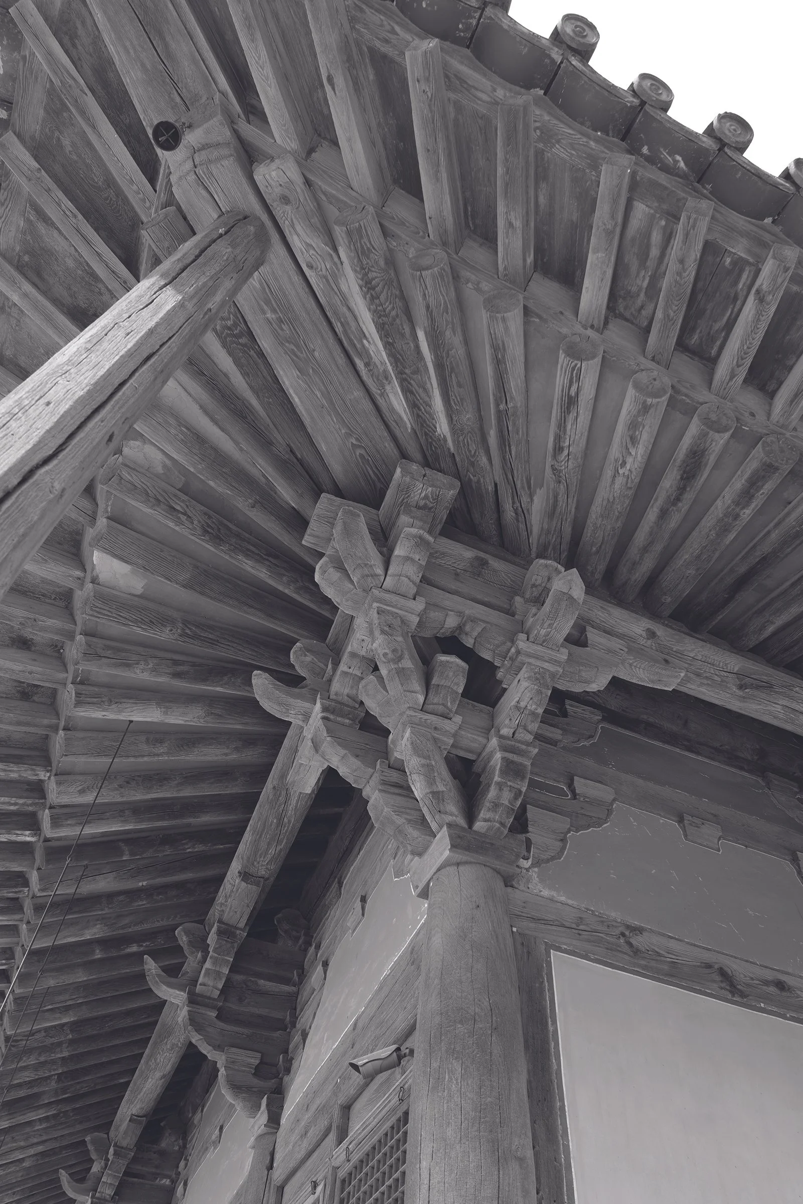 Black and white photo of a traditional Asian wooden roof with curved eaves and supporting beams.