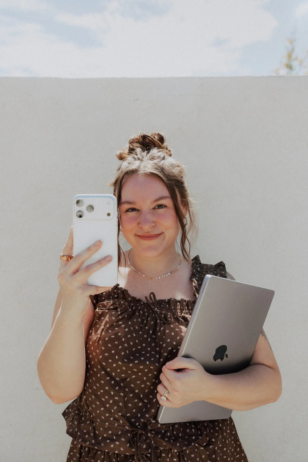 Calle Morain of Maison Morain filming content on her phone with a laptop under her arm