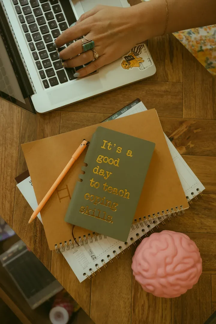 Therapist's desk with laptop, notebooks and a brain model, set up for a coping skills group or staff training