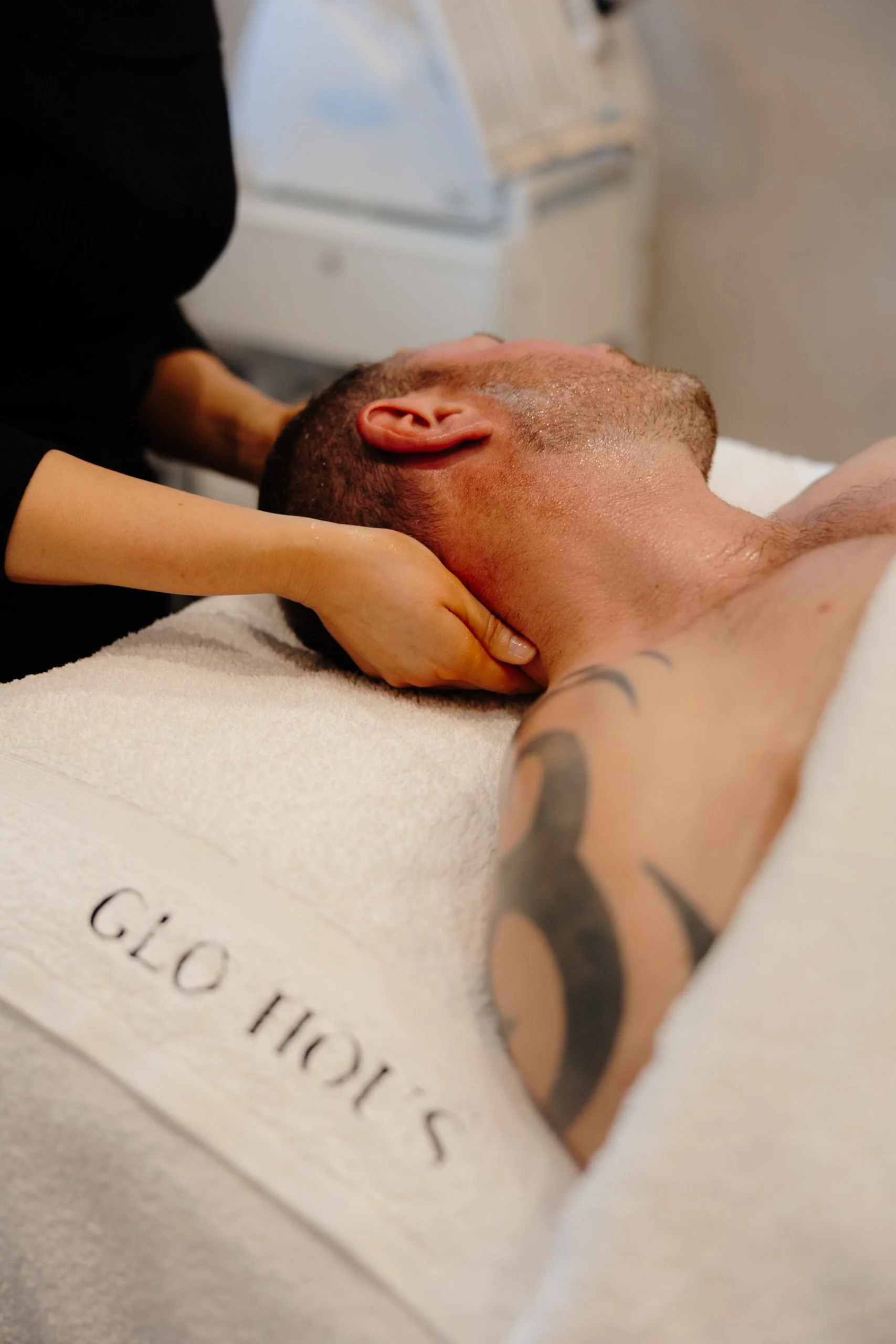 Close-up of a man receiving a massage, lying on a massage table with a white towel, in a spa or massage room.