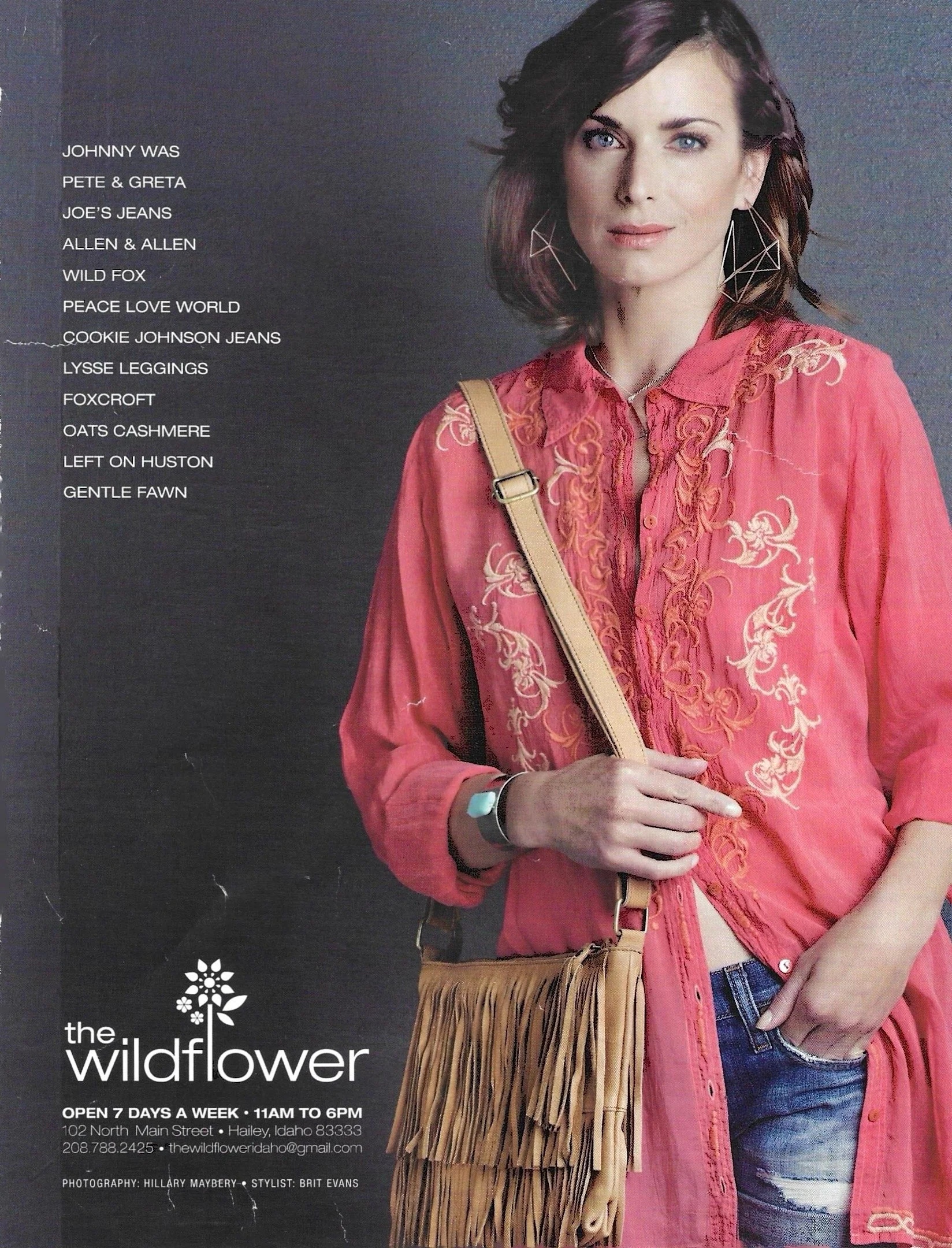 A woman wearing a pink embroidered shirt with earrings and a silver necklace, standing next to a fringed tan purse, with text about The Wildflower store on the left side of the image.