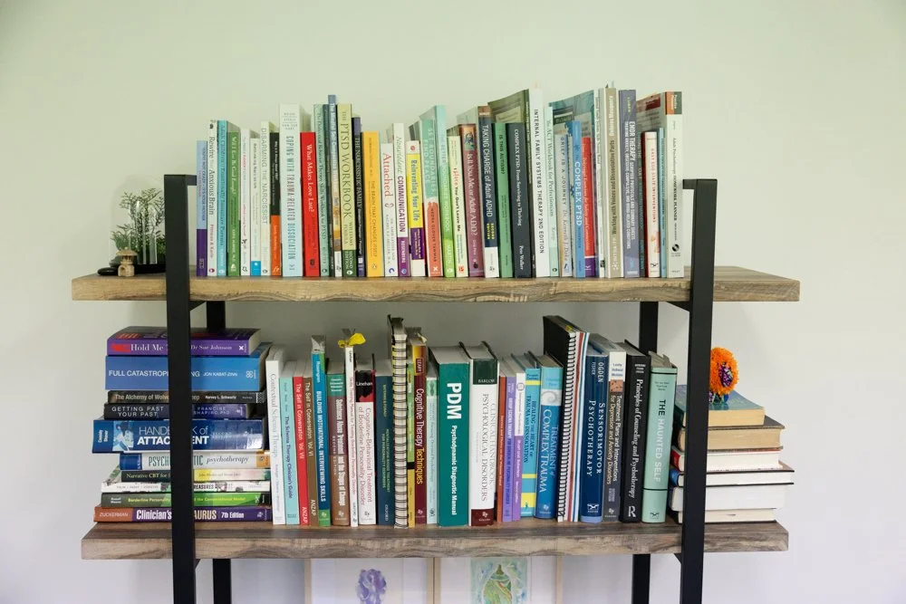 Bookshelves with psychology books, plants and decorative objects in the consulting room.