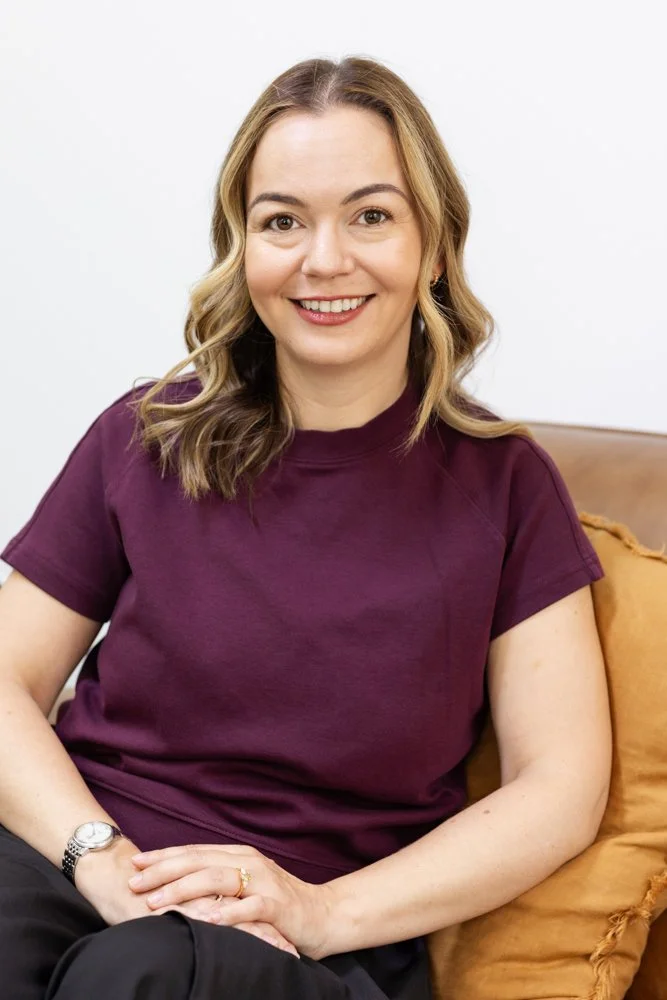 Clinical psychologist Irina Petrova seated on a brown sofa in her North Sydney consulting room.