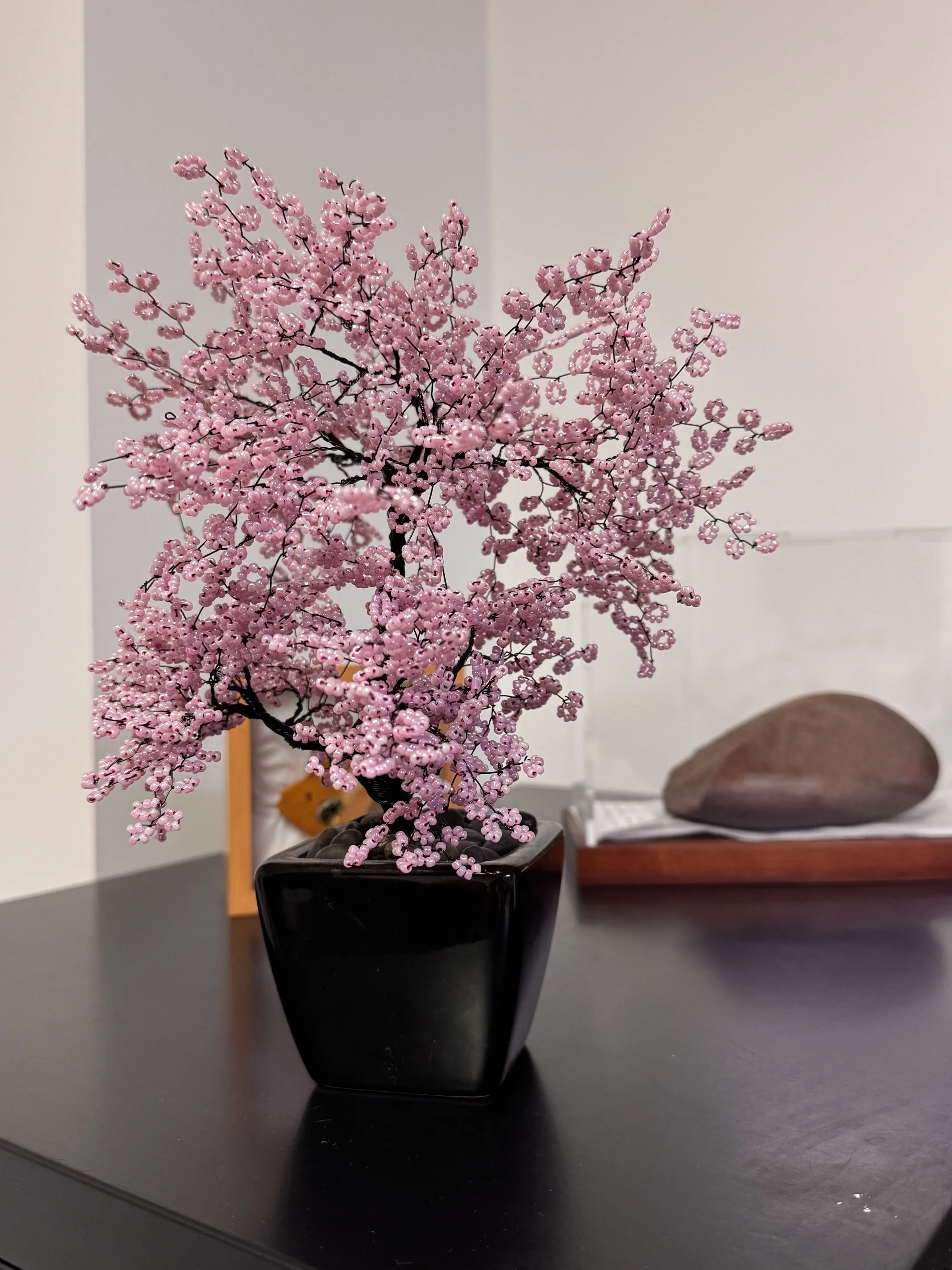 Pink beaded cherry blossom tree beside a display of an early stone tool.