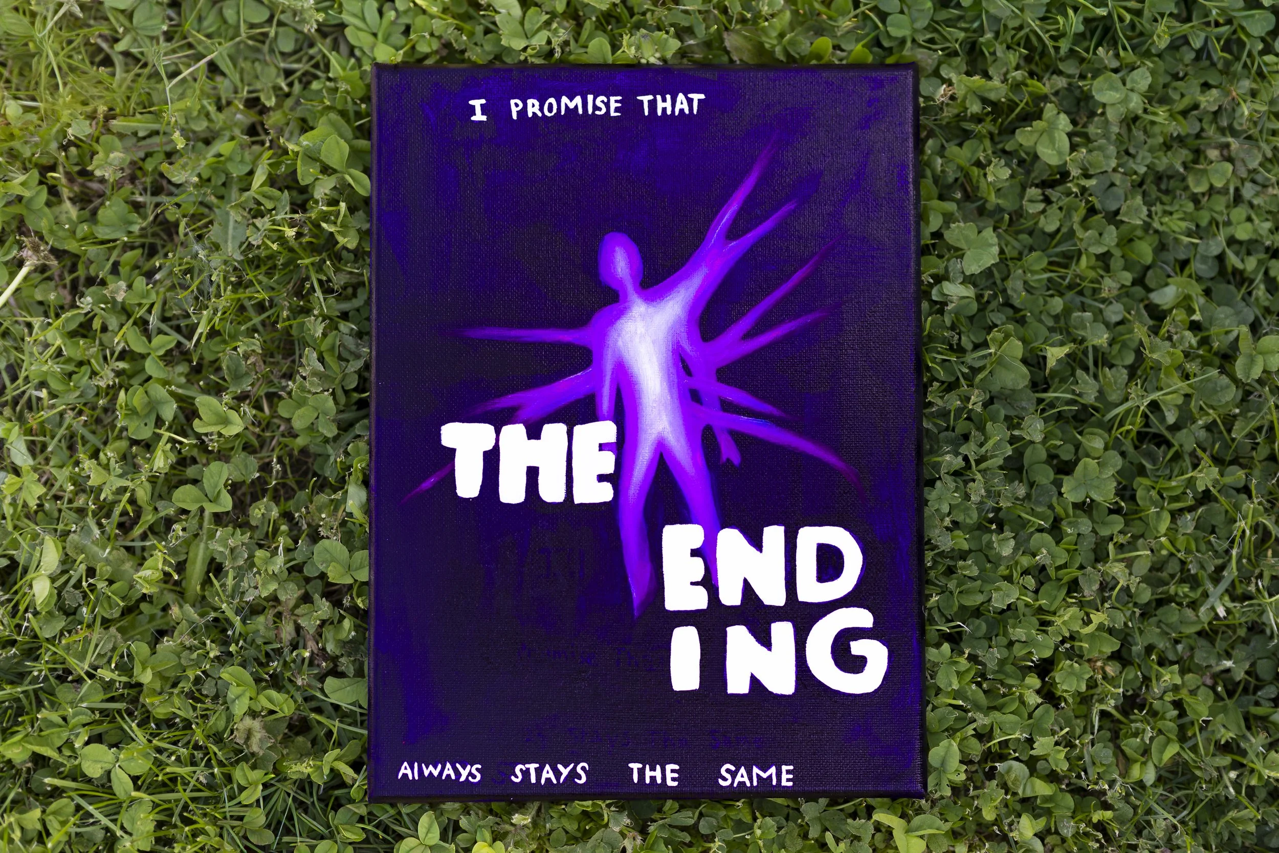 A rectangular sign lying on a bed of green clover leaves. The sign has a purple background with white text. It features a purple, glowing neural or neuron-like illustration and the words 'I PROMISE THAT THE END' and 'ALWAYS STAYS THE SAME'.