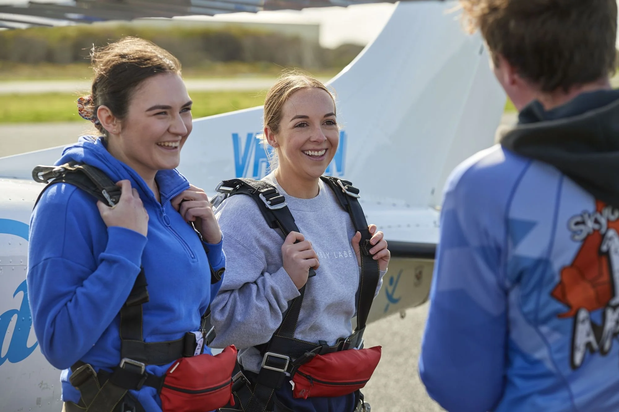 Two tandem skydivers in harnesses ready to board the skydiving plane