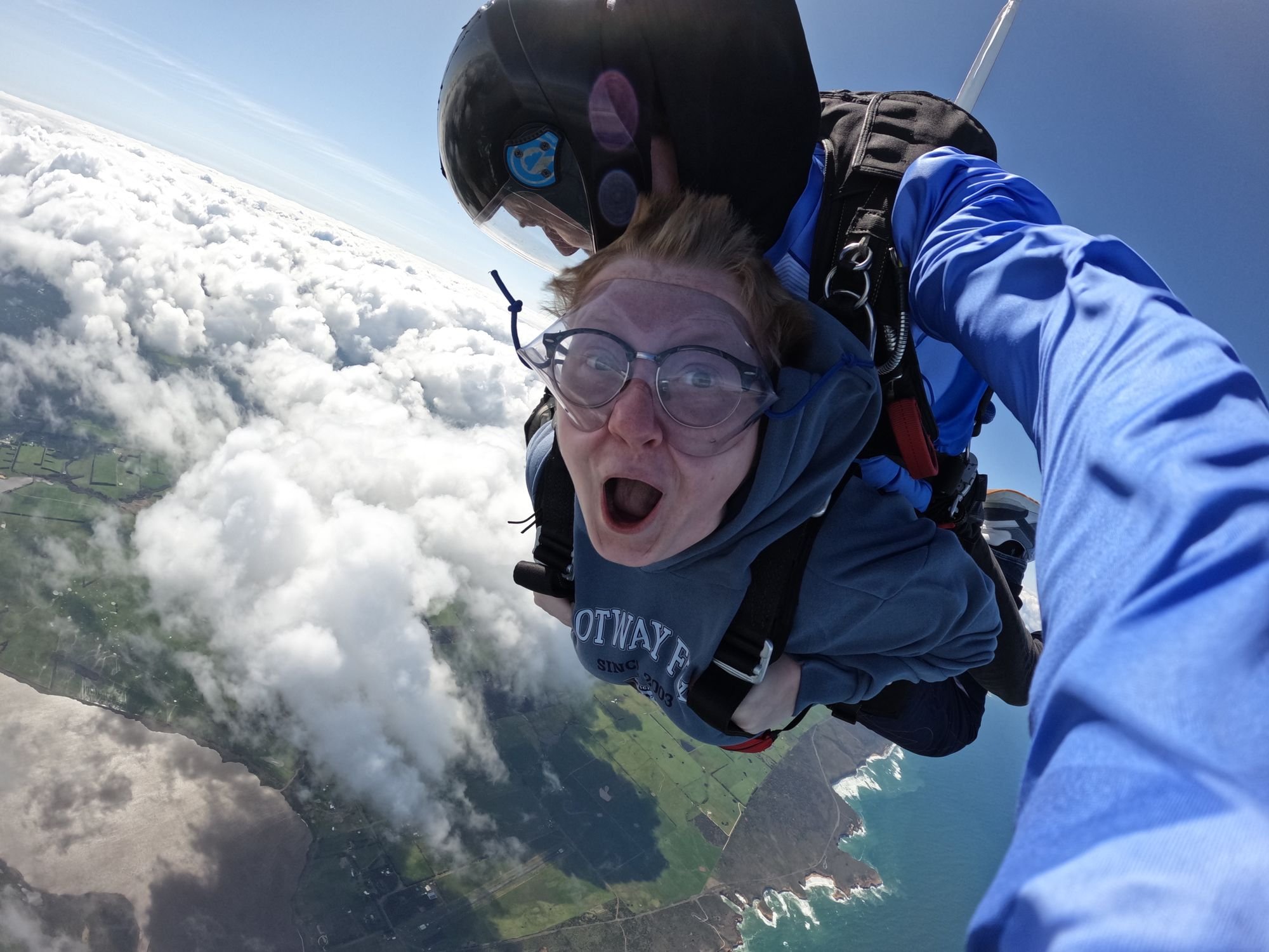 Tandem skydiver in freefall above the clouds and the Great Ocean Road coastline