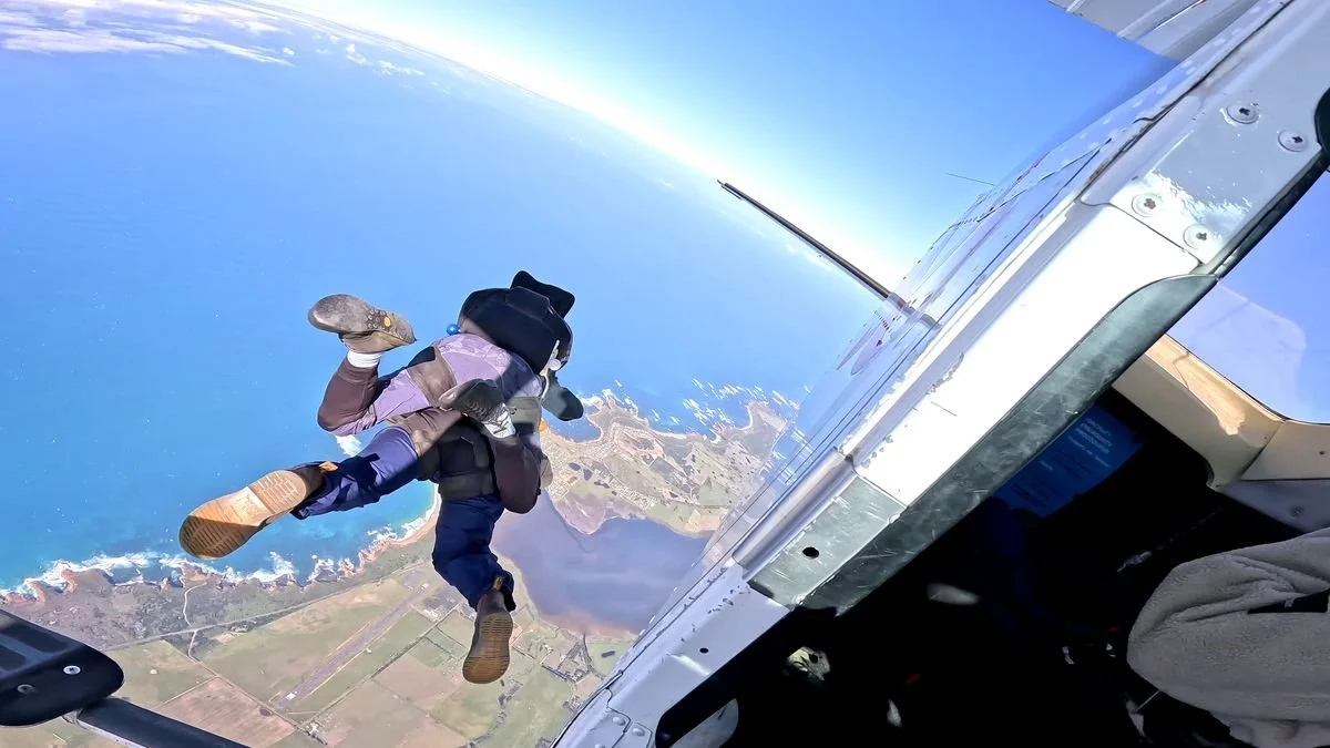 Tandem skydivers exiting the plane above the 12 Apostles coastline