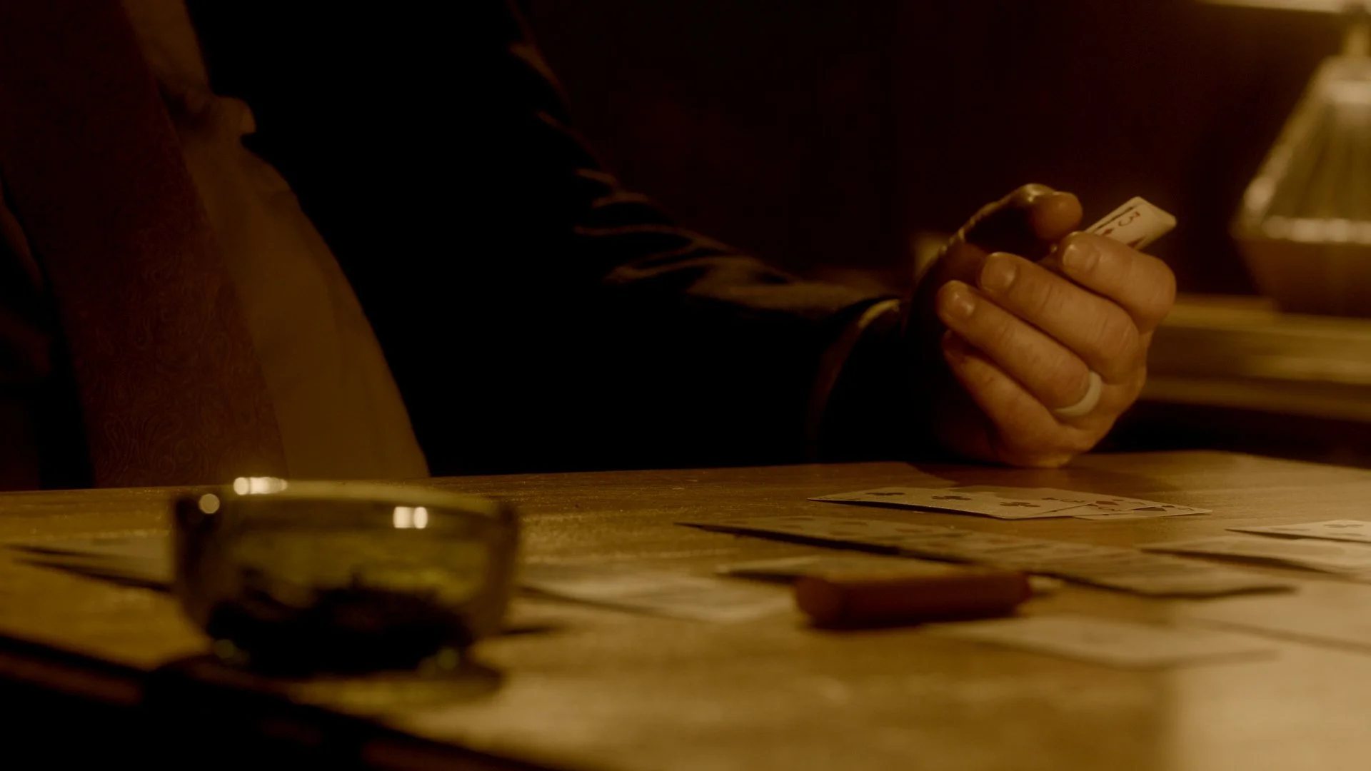 Person holding a playing card in a dimly lit room.