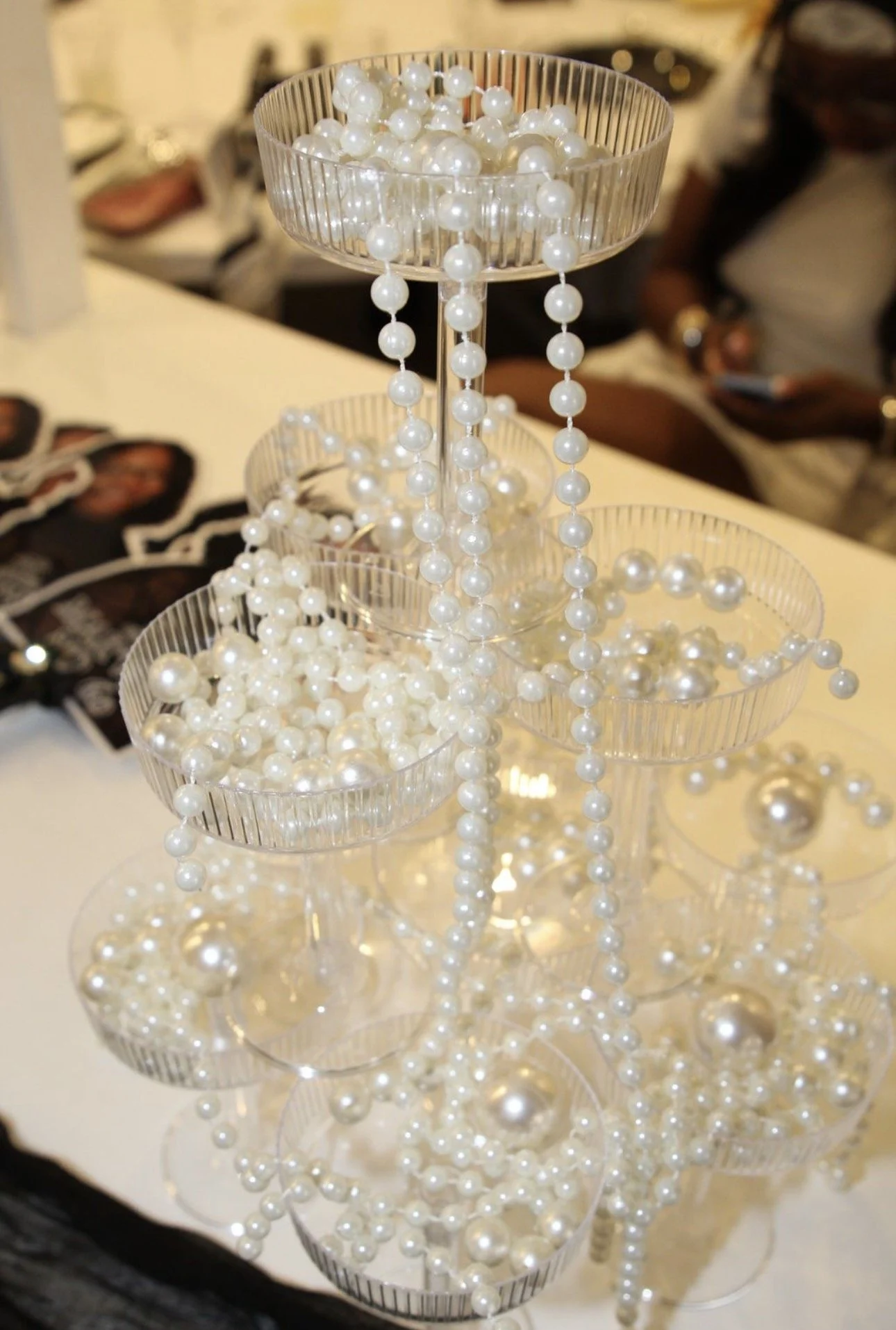 Display of pearl necklaces on a multi-tiered clear acrylic stand at a jewelry boutique or market. Philadelphia event planner, Philadelphia birthday planner. Philadelphia decorating, design, planning, and event management