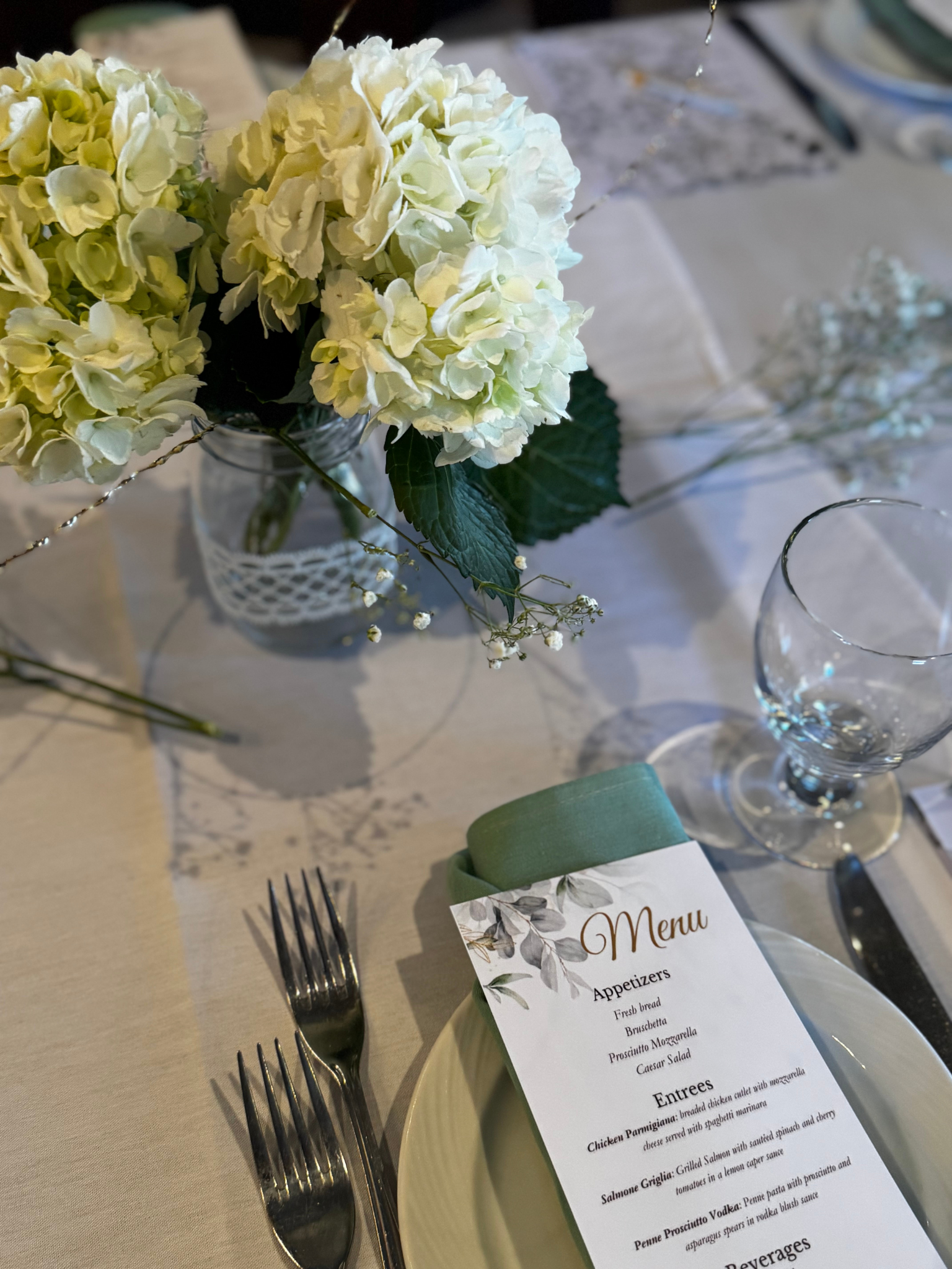 A wedding table with a floral centerpiece of white hydrangeas, a menu card, cutlery..Philadelphia event planner, Philadelphia bridal shower, Philadelphia birthday planner. Philadelphia decorating, design, planning, and event management