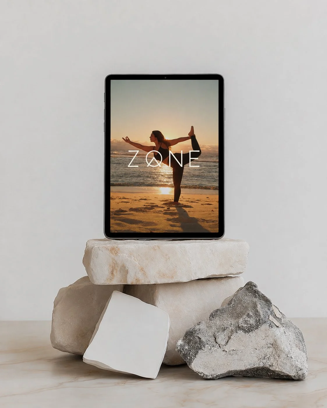 ZONE by Lydia activewear and yoga brand identity by HOLOS, shown on a tablet resting on natural stones