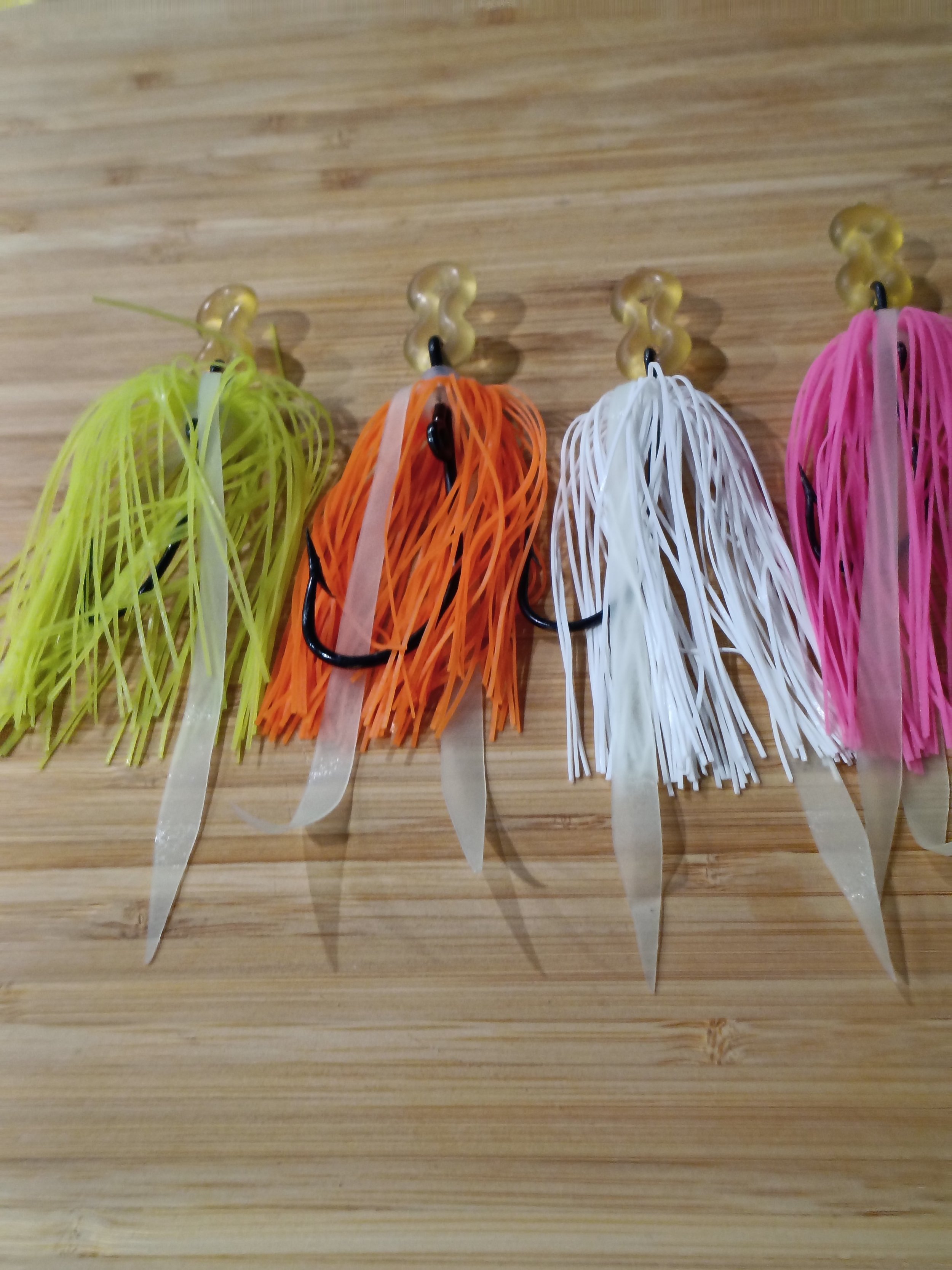 Colorful plastic fishing lures hanging on hooks against a wooden background.