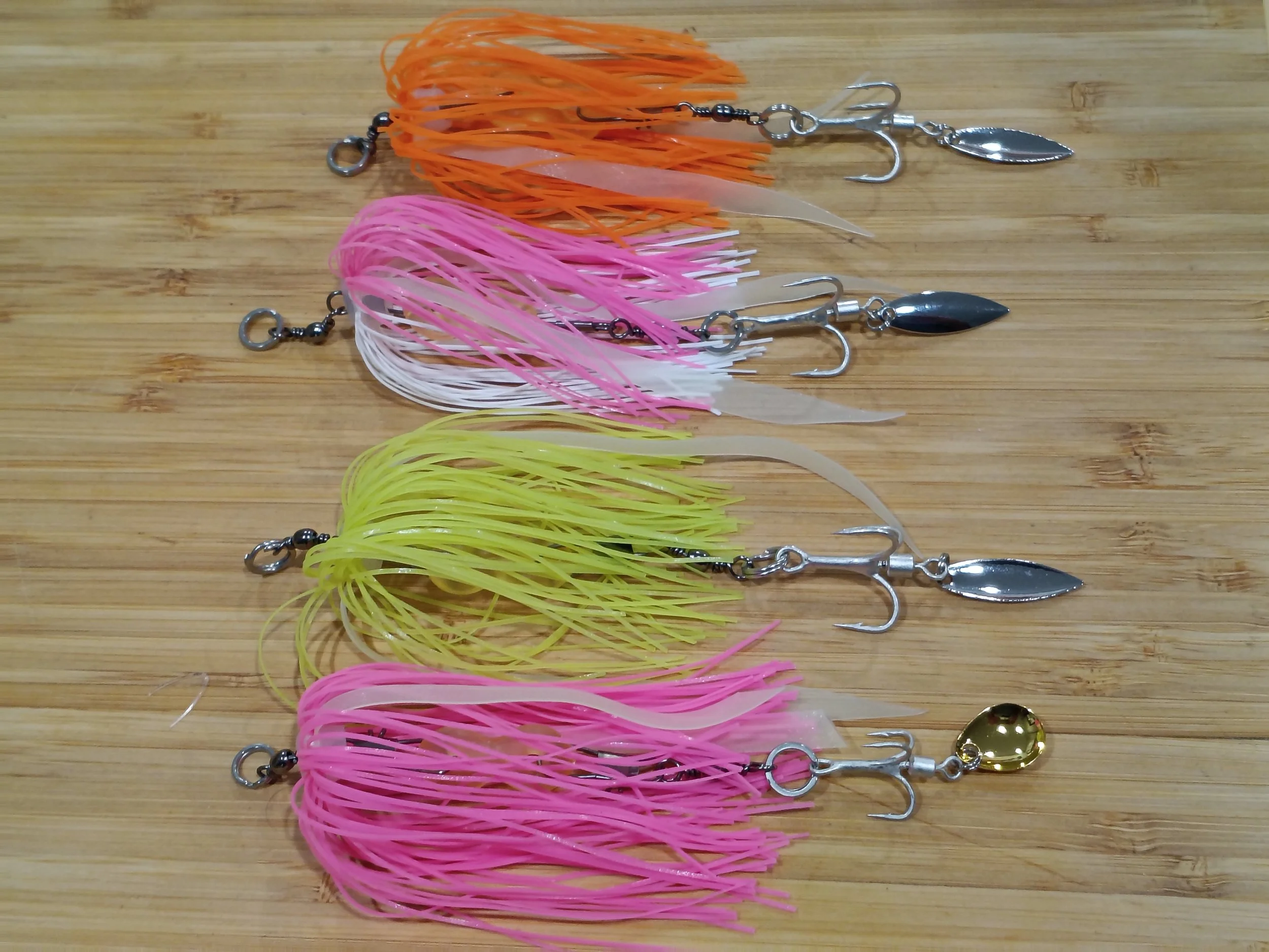 Multiple colorful fishing lures with blades and hooks laid out on a wooden surface.