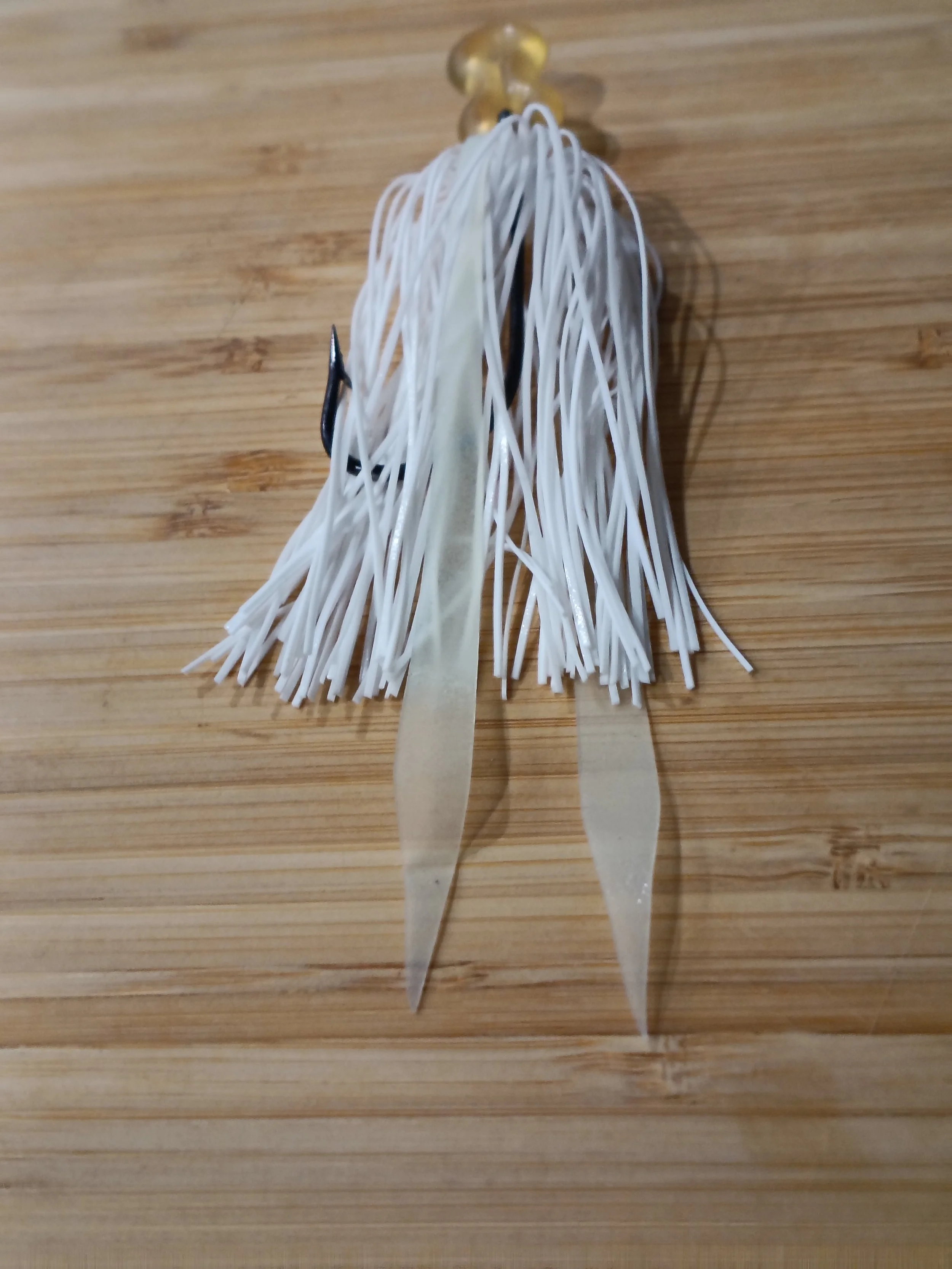 Two strips of uncooked flat pasta, one black plastic clip, and a pair of tongs on a wooden surface.