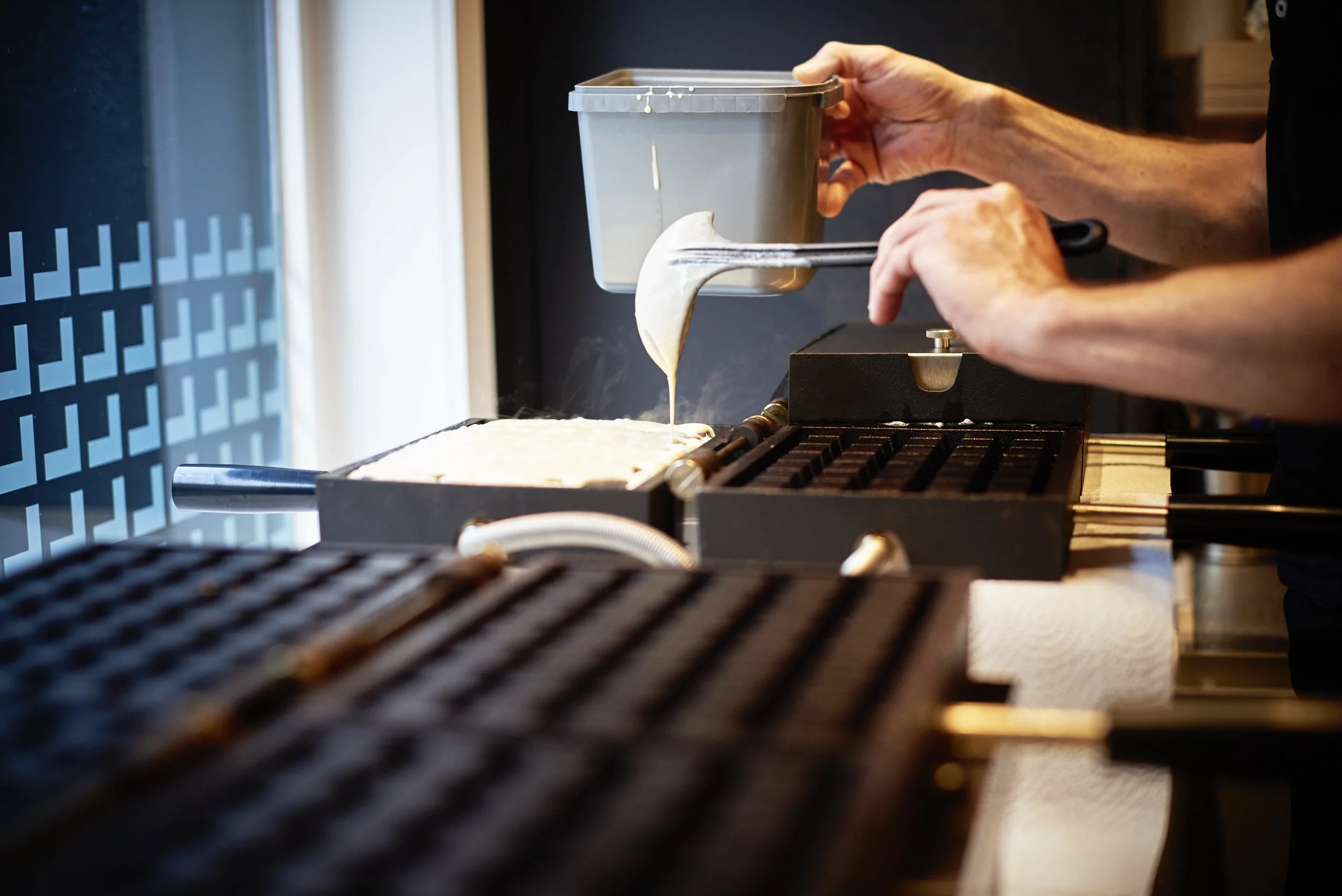 Frederick giet wafelbeslag in het wafelijzer
