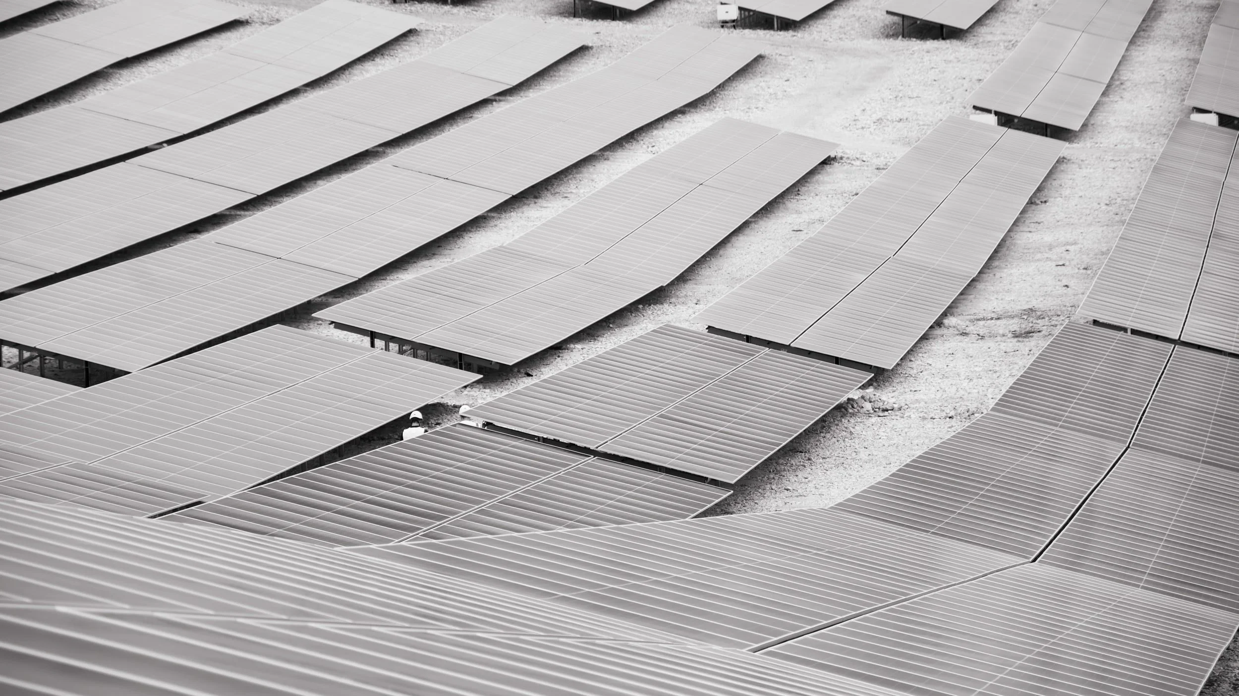 An aerial view of multiple solar panels installed on a flat surface in a grid pattern.