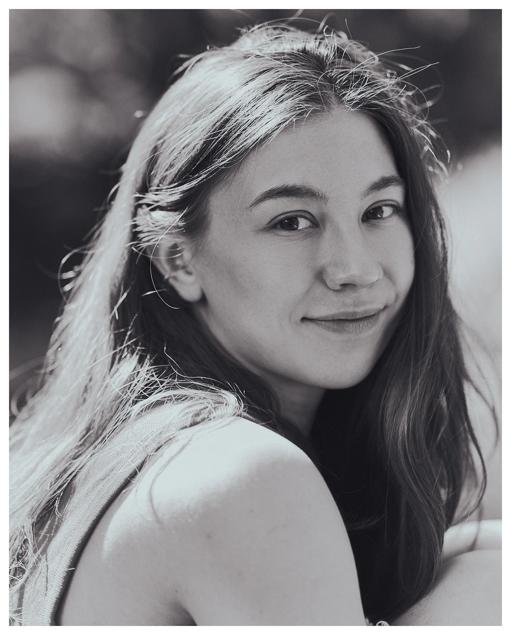 Close-up of a young woman's face with long hair, smiling, in black and white.