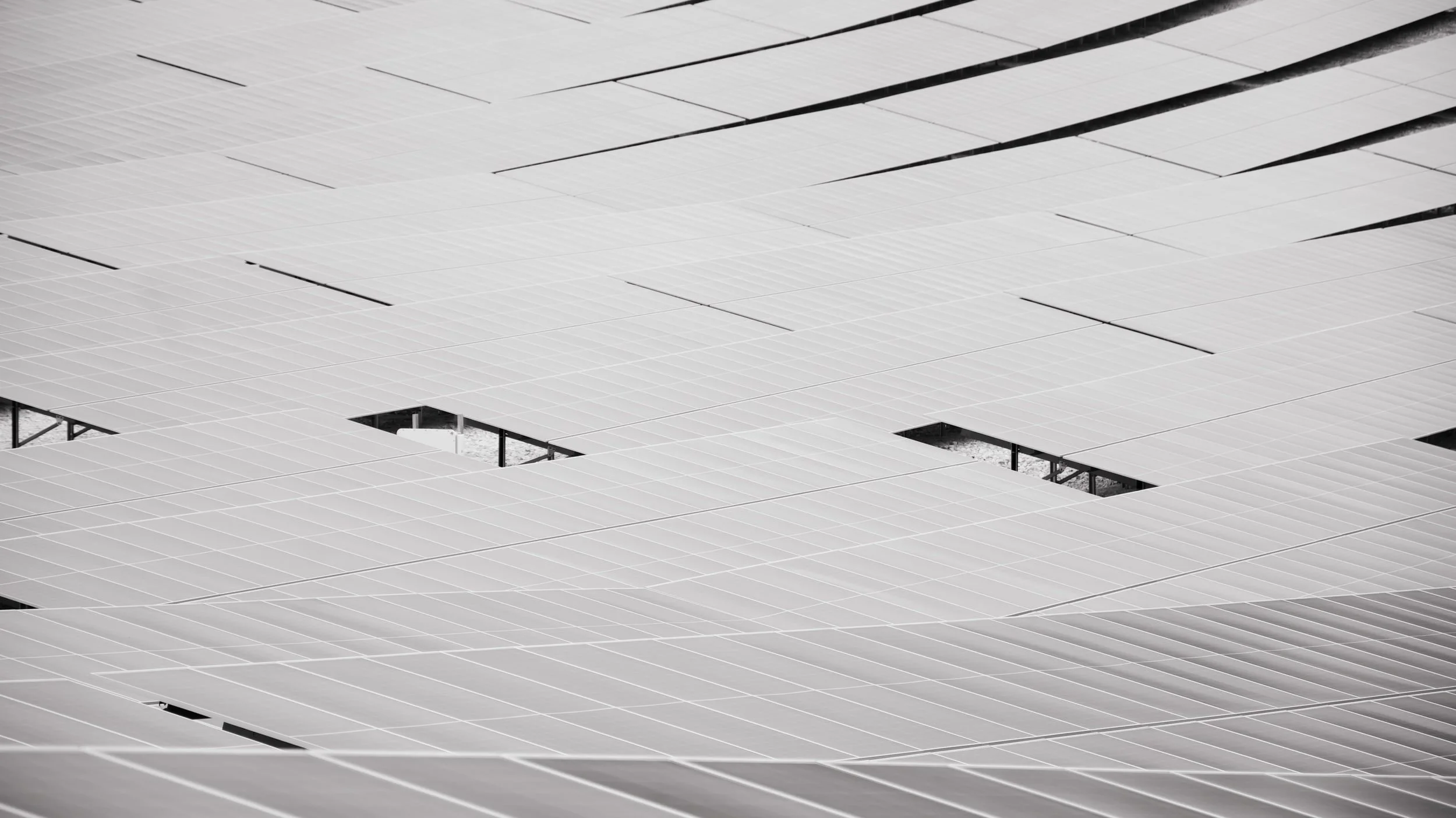 A large array of solar panels installed on a rooftop or ground surface, arranged in rows to capture sunlight.