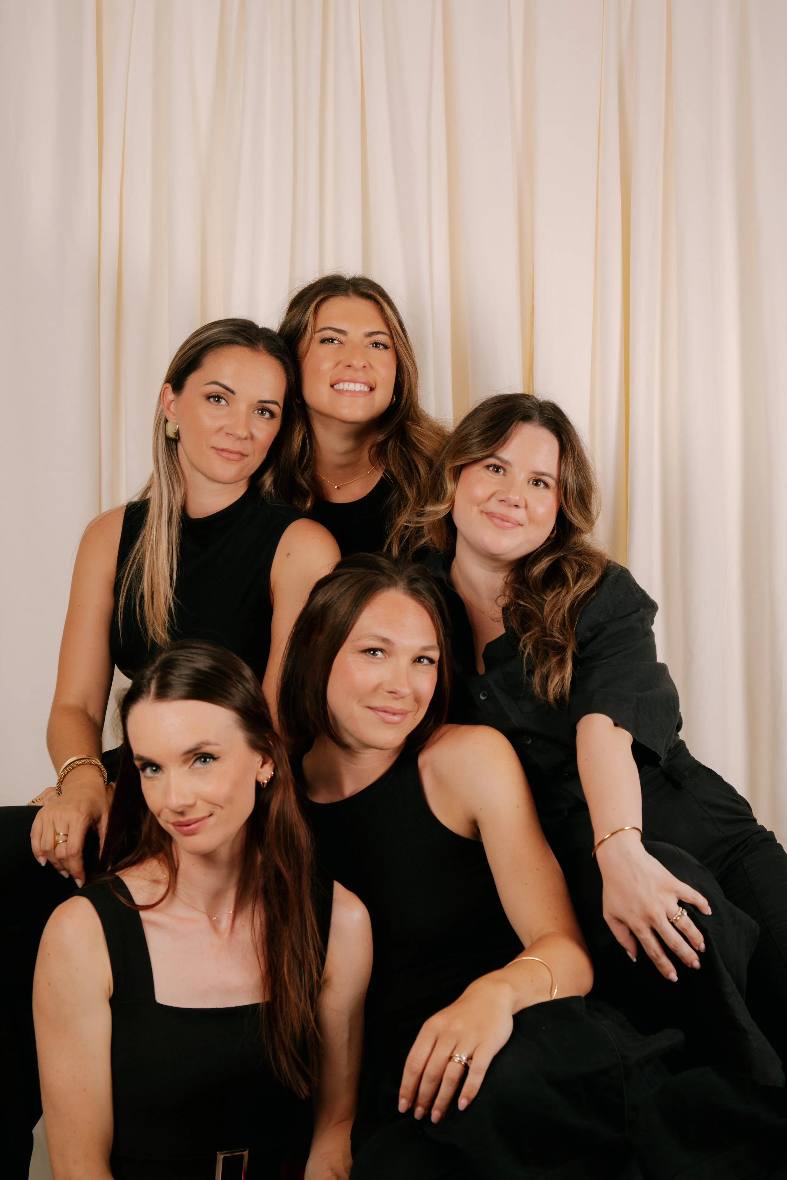 Groupe de femmes posant devant un rideau blanc.